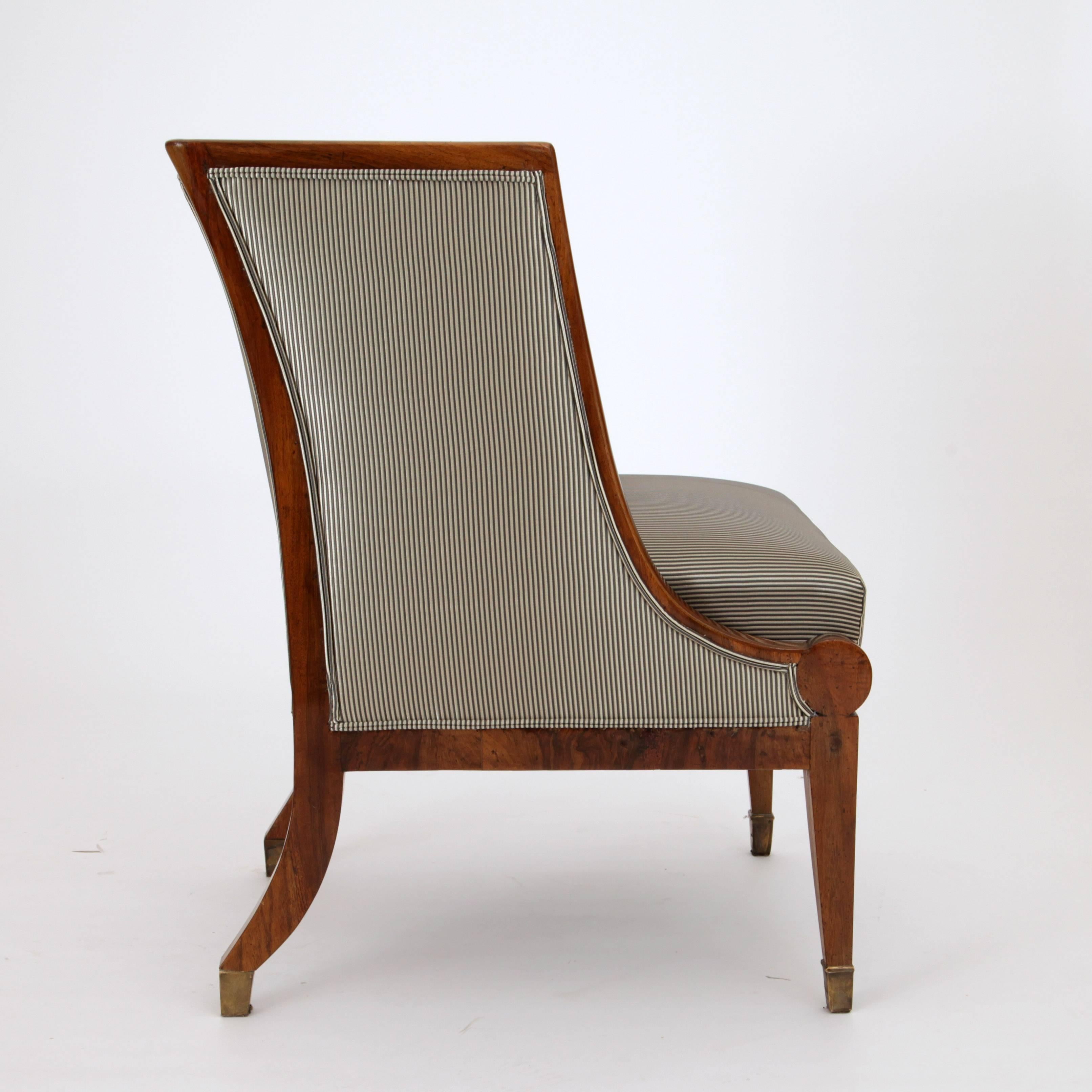 Biedermeier bergère chair on tapered legs with brass sabots. The rear legs are slightly bent. The backrest has a straight edge and is in a right angle to the C-shaped sides. The chair is newly upholstered in a very beautiful and high-quality fabric.