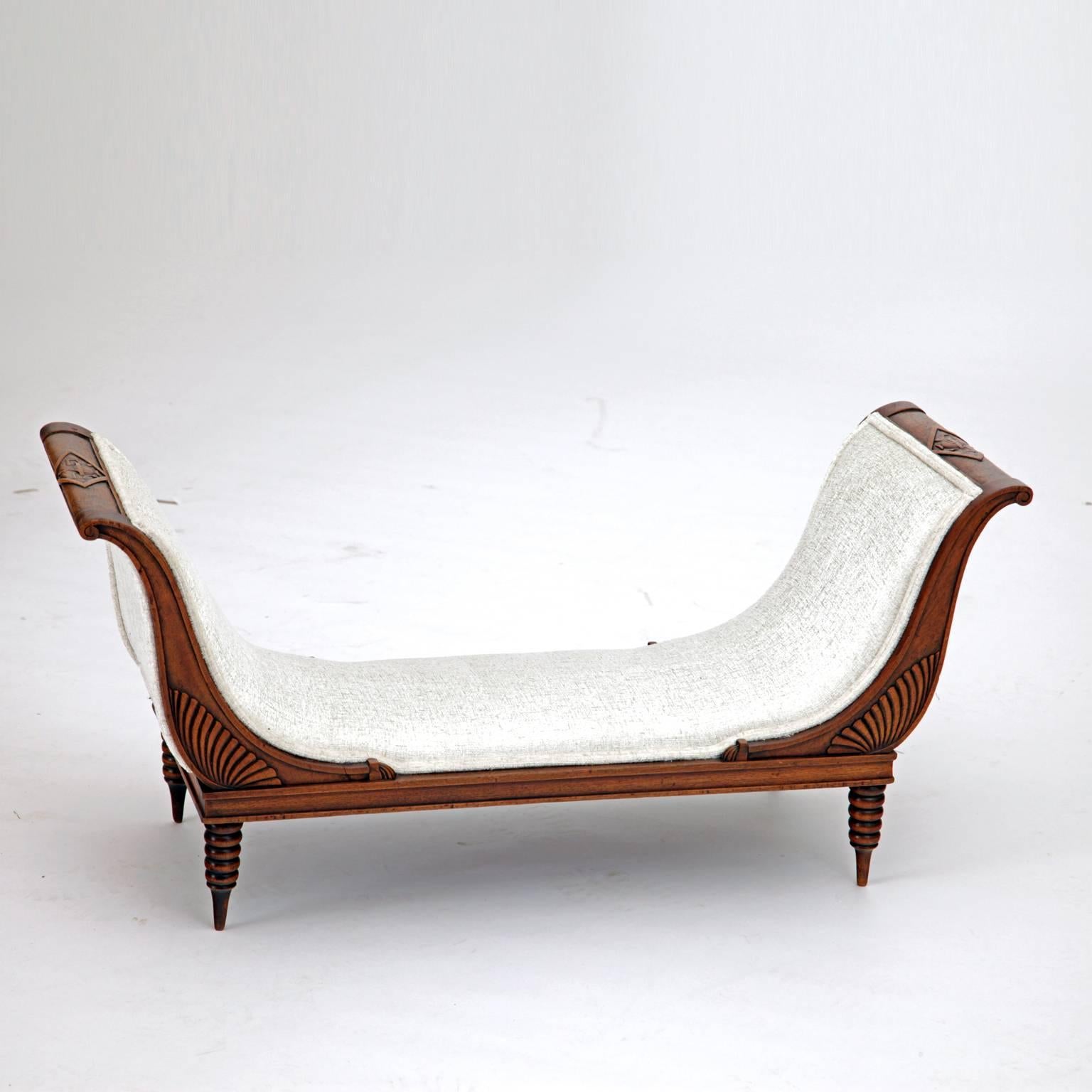 Extraordinary miniature bench with sled-shaped sides and carved urn-motives. The bench is newly upholstered with a high quality silver-white fabric.