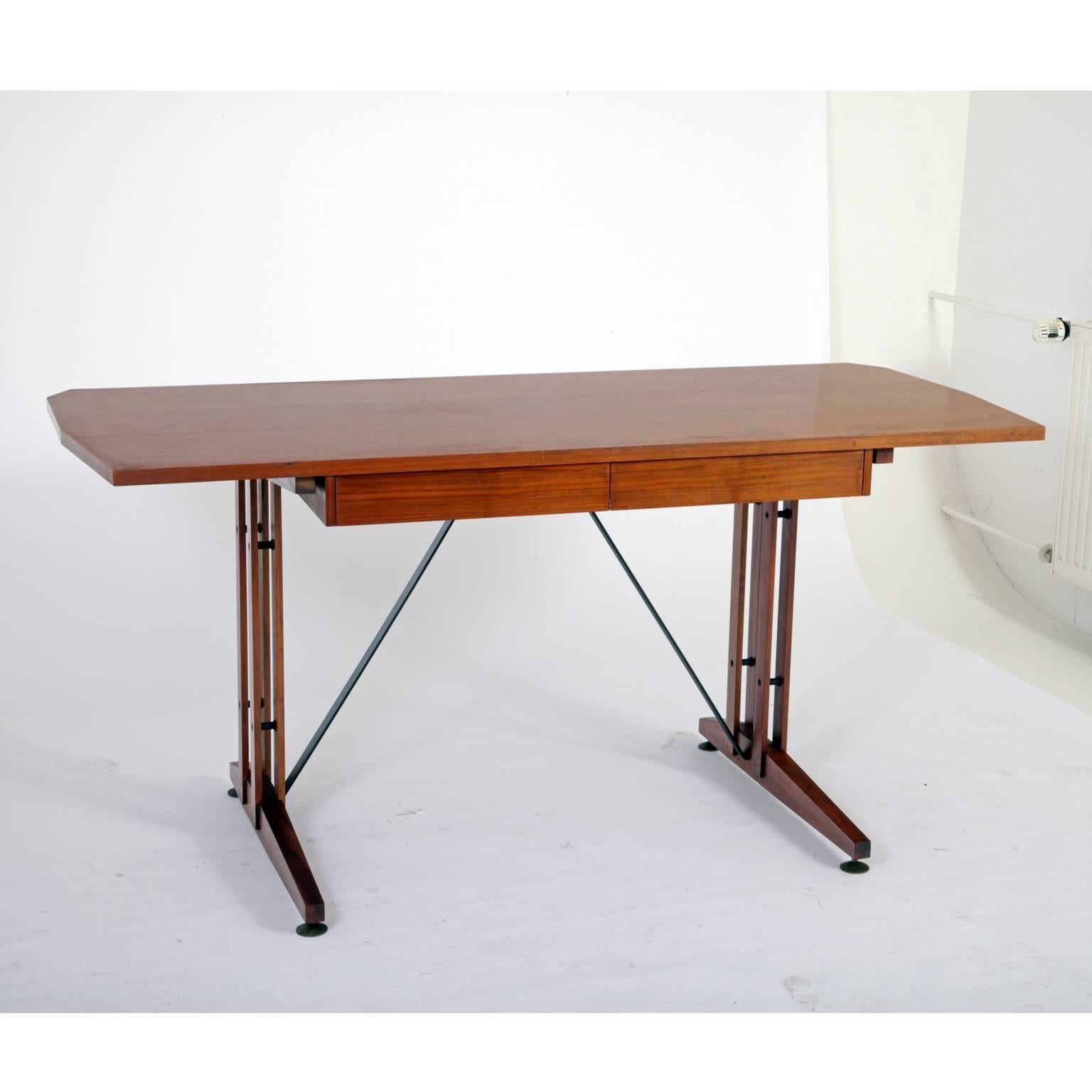 Large Mid-Century desk with two drawers. The tabletop is angular on the smaller sides. The legs stand on round brass feet and are supported by ironstruts.