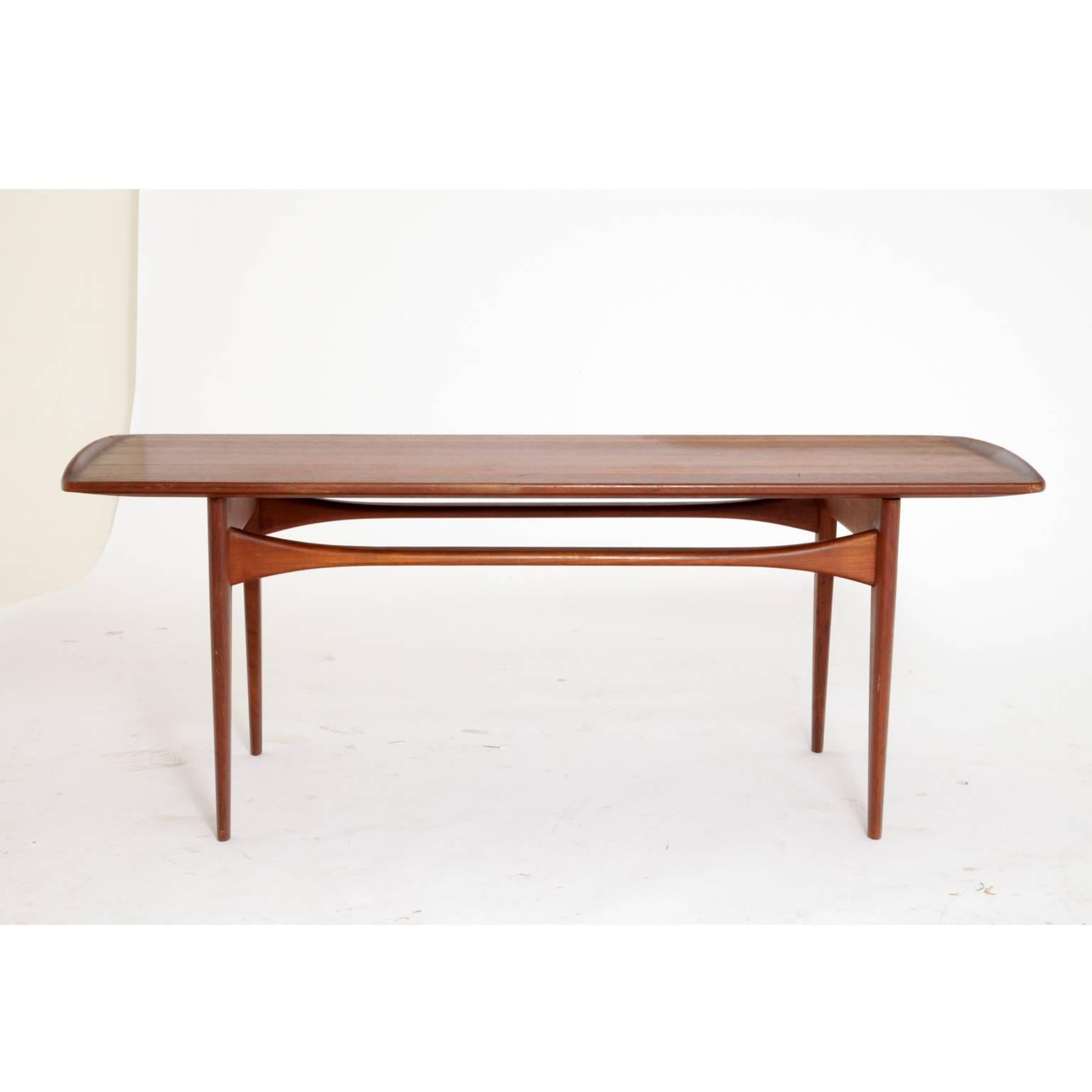 Organically formed coffee table by the Danish designer couple Tove and Edvard Kindt-Larsen. The table is made of teak and stands on tapered legs. The struts are getting smaller towards the centre while the tabletop rises a bit towards the small