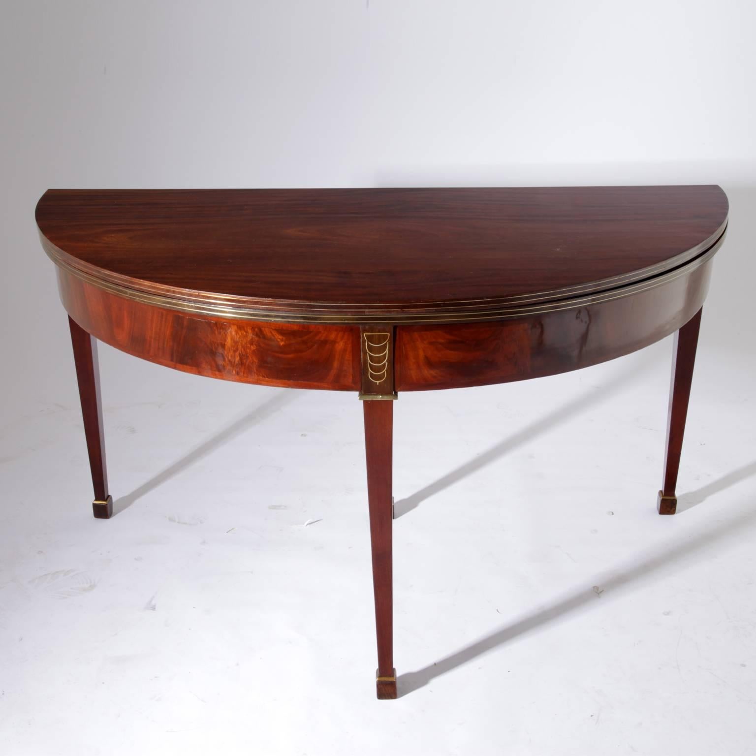 Demilune table by Jean-Joseph Chapuis on tapered legs with sickle-shaped brass inlays and a very beautiful mahogany veneer. The rear leg can be pulled out and is stamped 