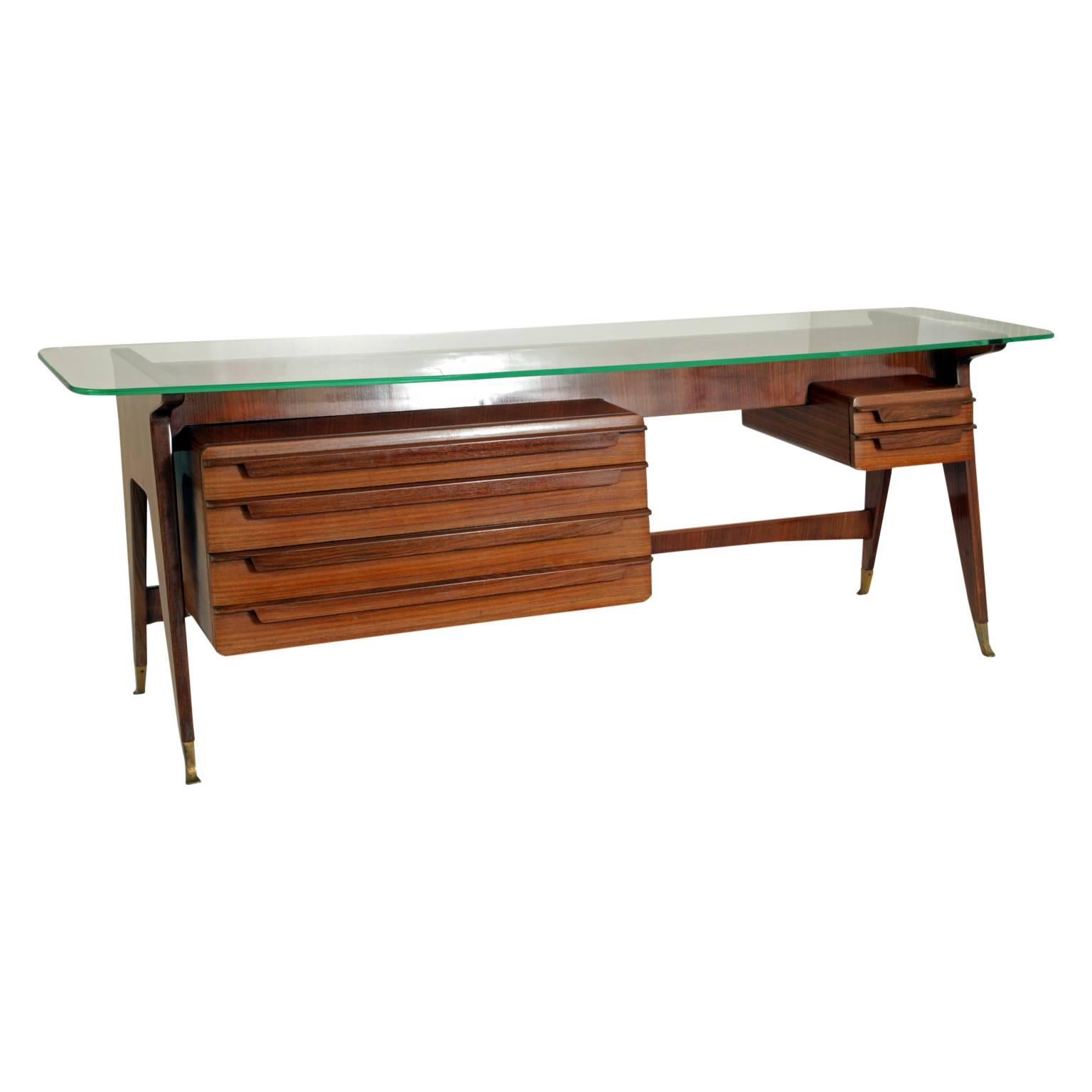 Low desk or dressing table on tapered legs with brass sabots. Beneath the glass tabletop with rounded corners are four broad drawers on the left and two smaller ones on the right.