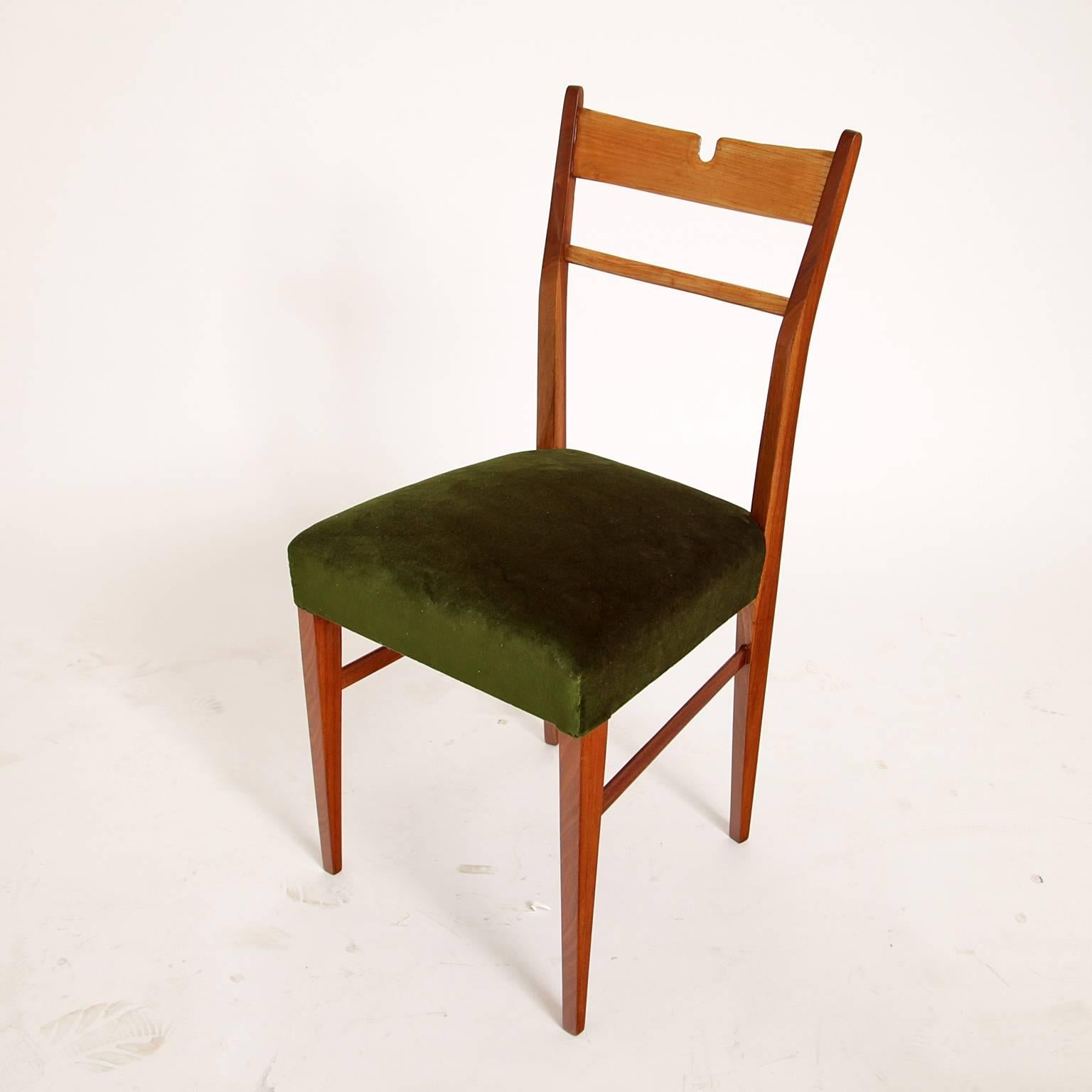 Four chairs on conical tapered legs. The backrest has a small strutting and a u-shaped cutout. The chairs are newly upholstered with a green, high quality velvet fabric.