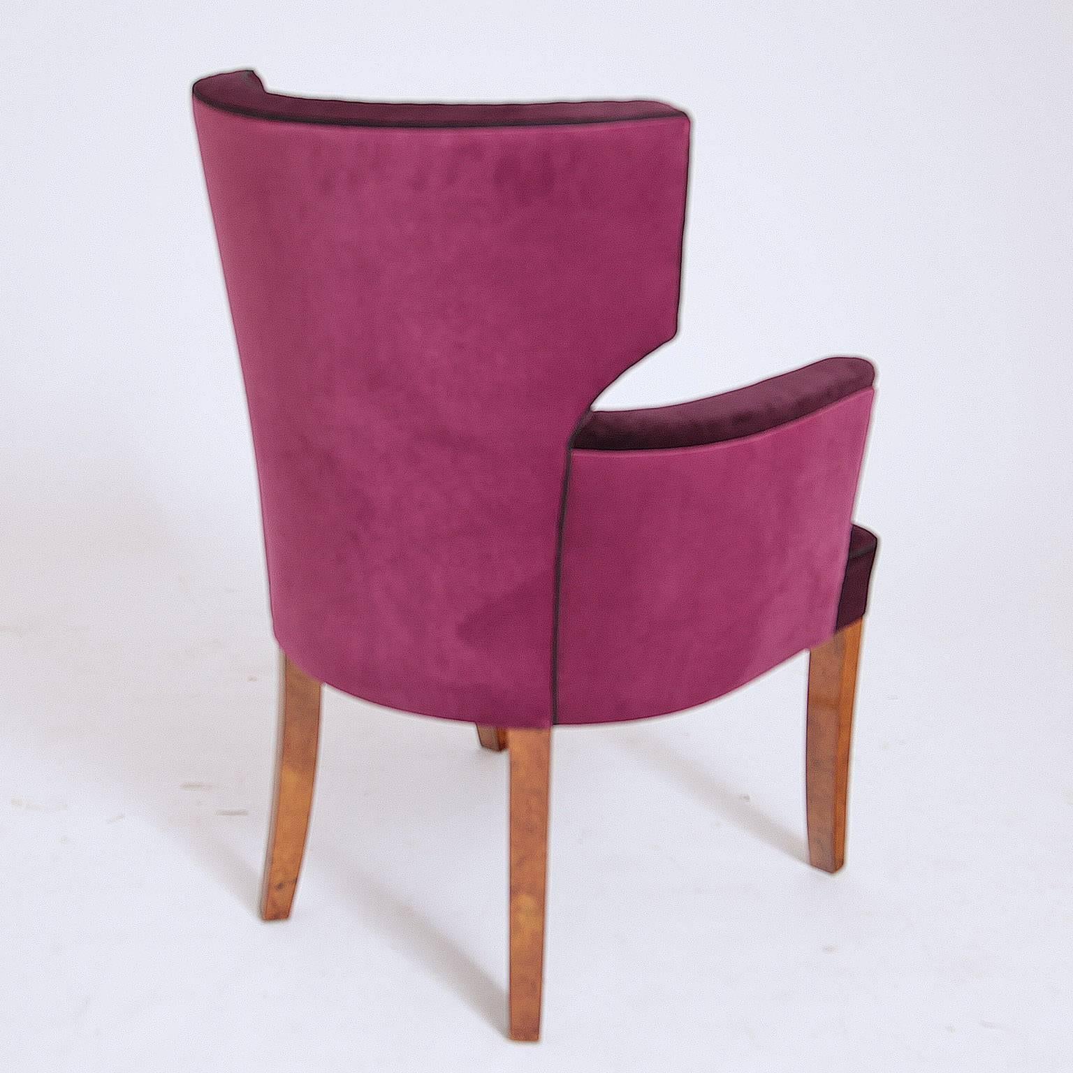 French armchair and chair with V-shaped backrests on slightly tapered legs. The chairs are upholstered with a dark violett colored velvet fabric.