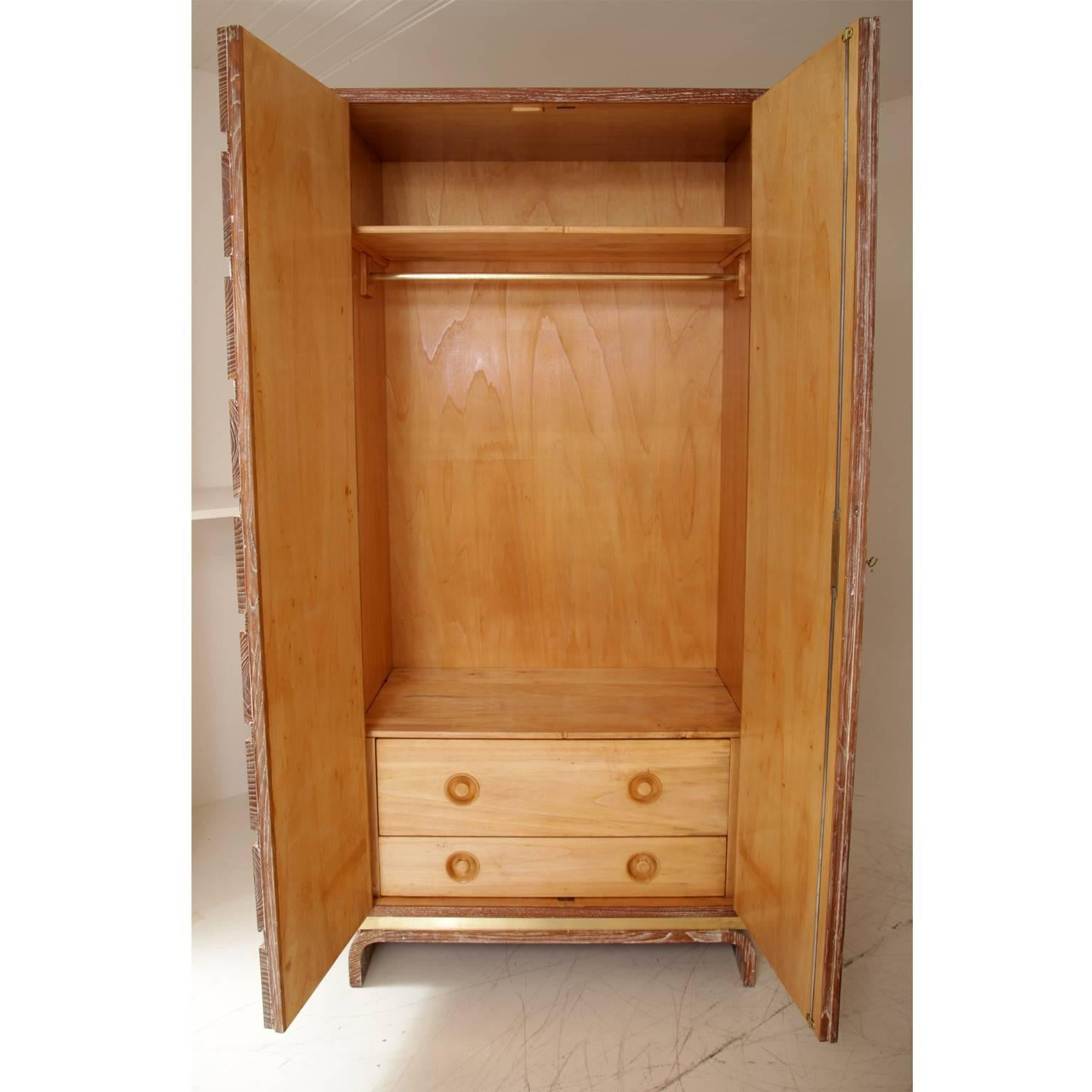 Large two-door wardrobe on a U-shaped stand with brass details. The limed finish emphasizes the beautiful oak grain. The interior consists of a clothing rack, one shelf and two large drawers.