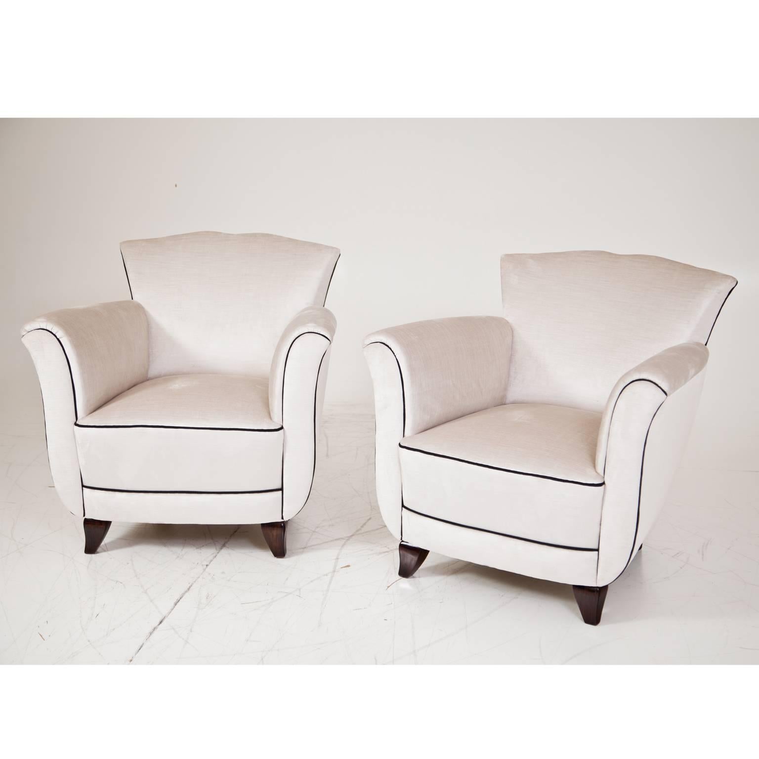Pair of armchairs on low tapered legs with thickly upholstered seat. The white fabric is accentuated by a black trim, which emphasizes the very beautiful and unusual lip-shaped backrest.