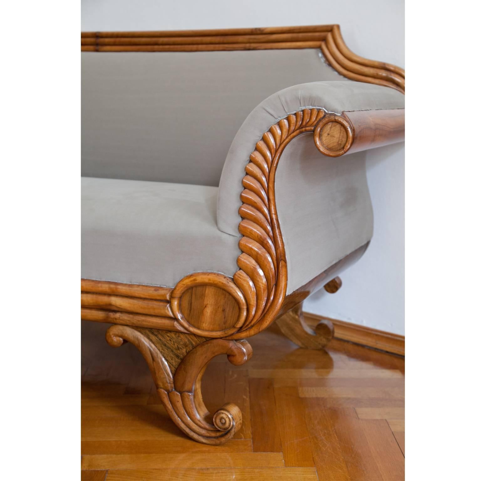 Very beautiful Biedermeier sofa on carved feet in the shape of fluted scroll ornaments. The s-shaped armrests are decorated with beautiful stylized fern ornaments. The backrest is straight but curvy towards the corners. The threefold molding is