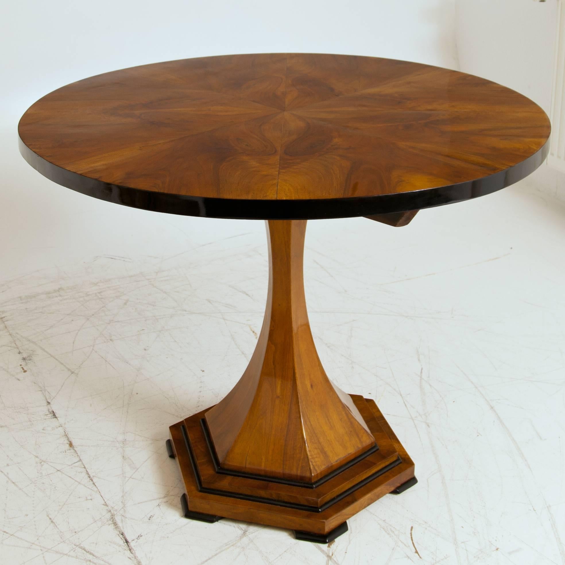 Biedermeier salon table on a hexagonal tapered column with ebonized mouldings. The tabletop shows a star-shaped mirrored veneer and has an ebonized edge. The table is in a very good restored condition.