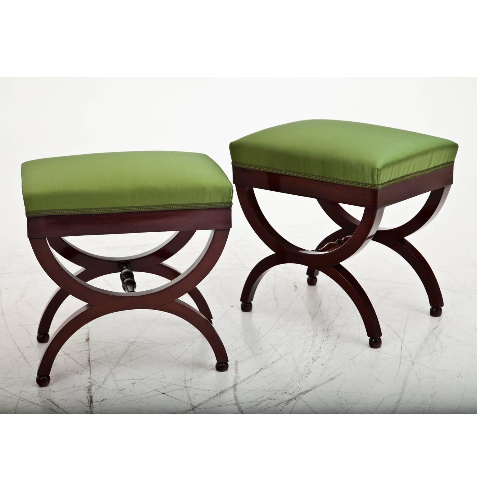 Pair of stools on X-shaped base with ball-feet and turned stretchers. The stools are restored and upholstered with a high quality fabric.