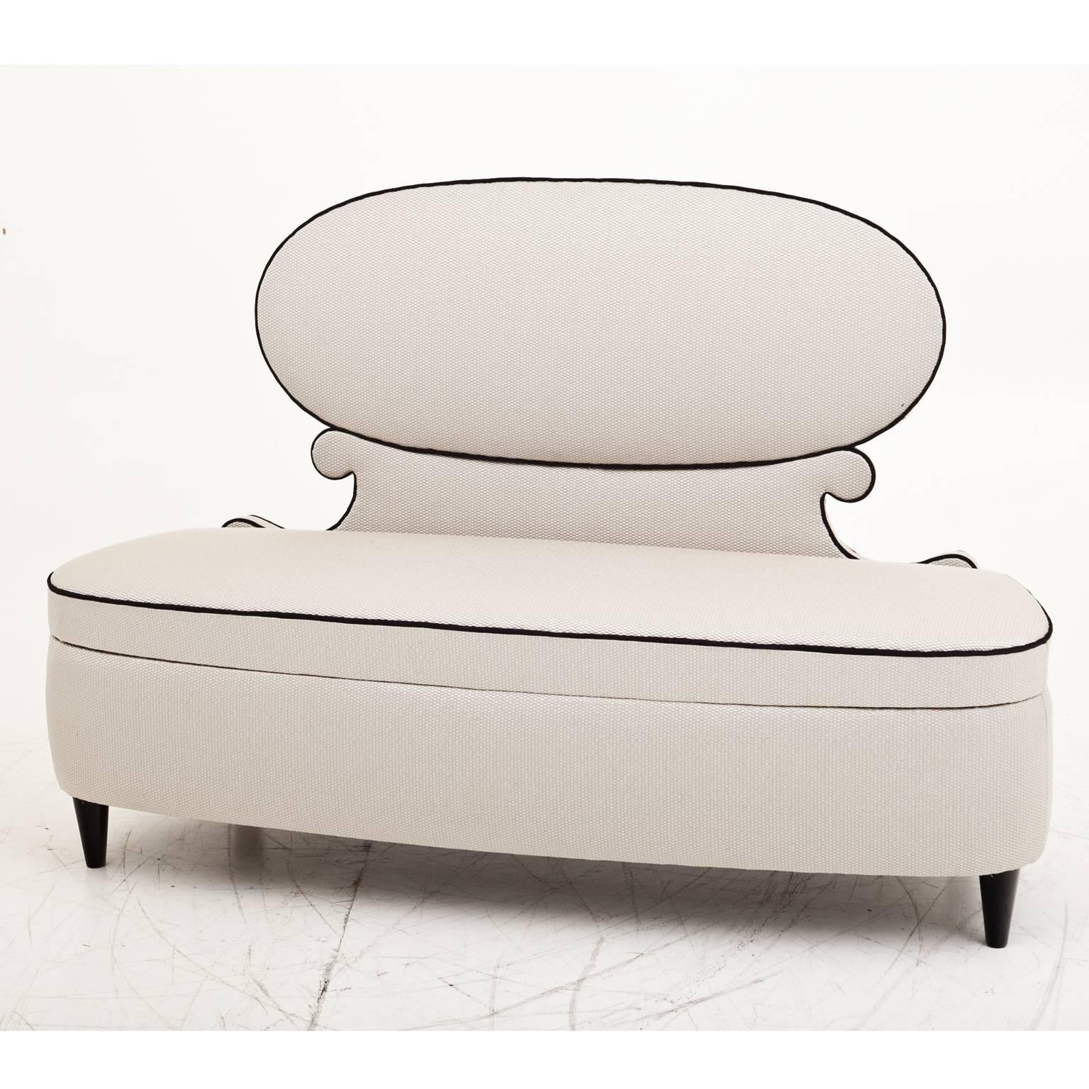 Elegant canapé sofa with a medaillon-shaped backrest and a rounded seat on black cone-shaped feet. The sofa is reupholstered with a beautiful, high quality fabric.