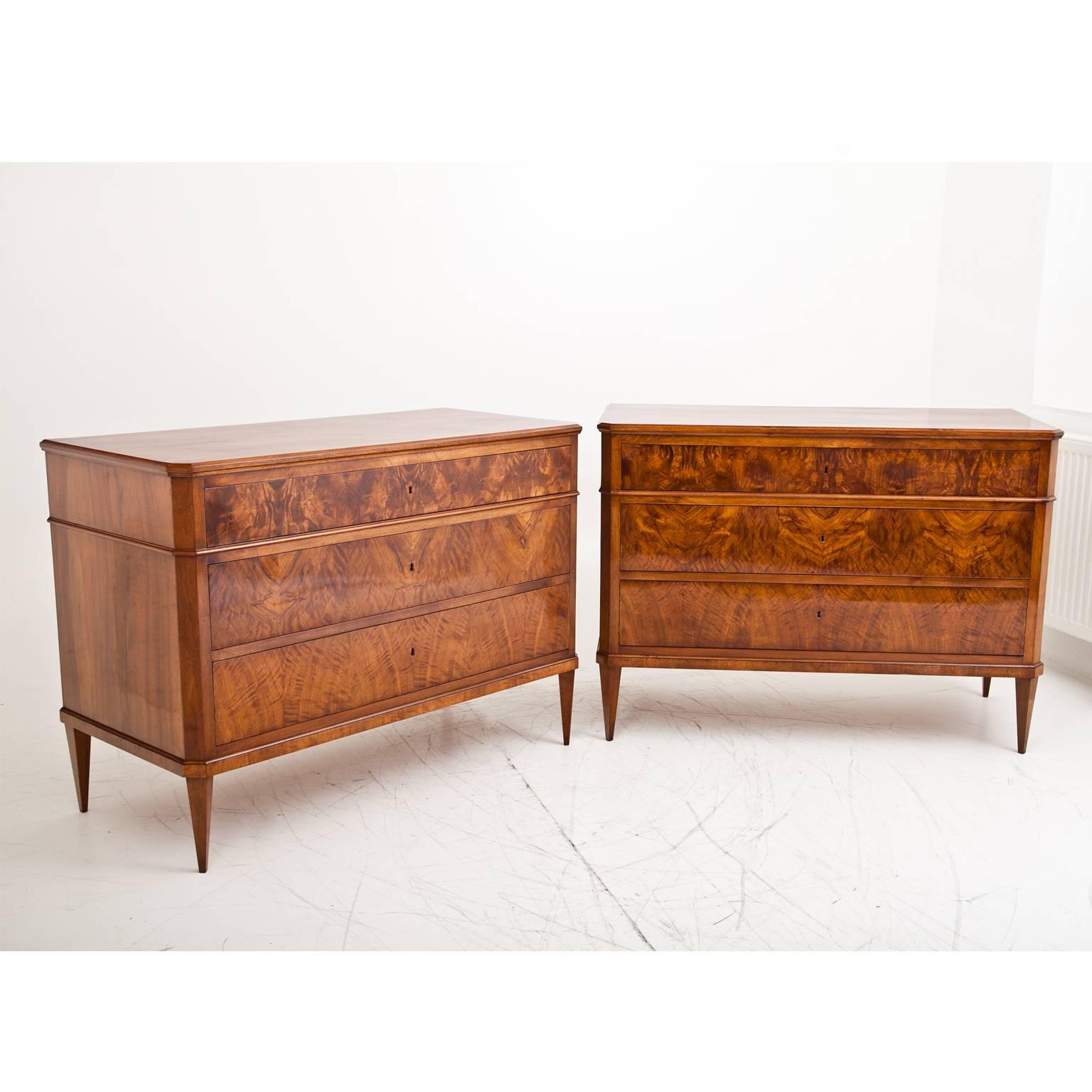 Pair of three-drawer chests of drawers on tapered feet, the body with slanted edges. The top drawer is accentuated with a moulding strip. The chests show a very beautiful walnut veneer pattern. They are restored and French polished.
