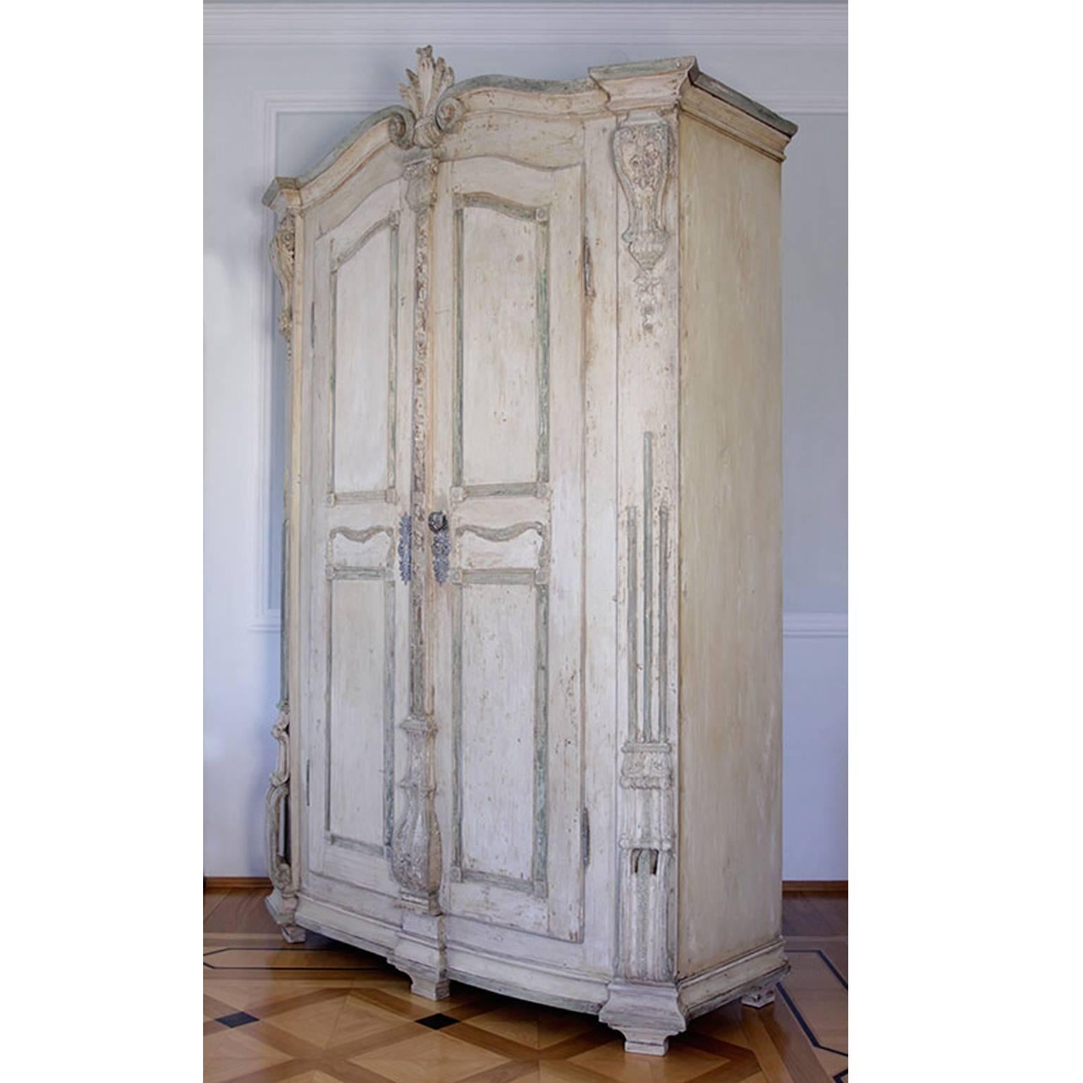 A cabinet with a spruce body retaining the original finish. The piece features a widely offset pilaster strip with acanthus leaf decoration together with perforated base volutes, a corresponding cleat, and a wavy crowning piece. The doors are