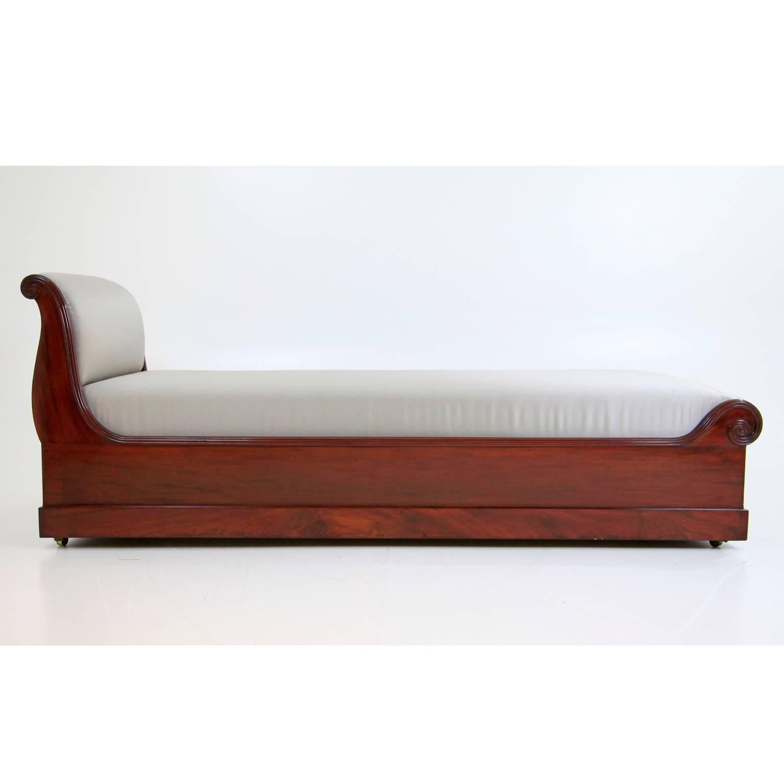 Elegant Biedermeier mahogany recamiere with a newly upholstered, grey satin cover and an S-shaped backrest. The chaise longue has a fluted edge, ending in scrolls and stands on little rolls.