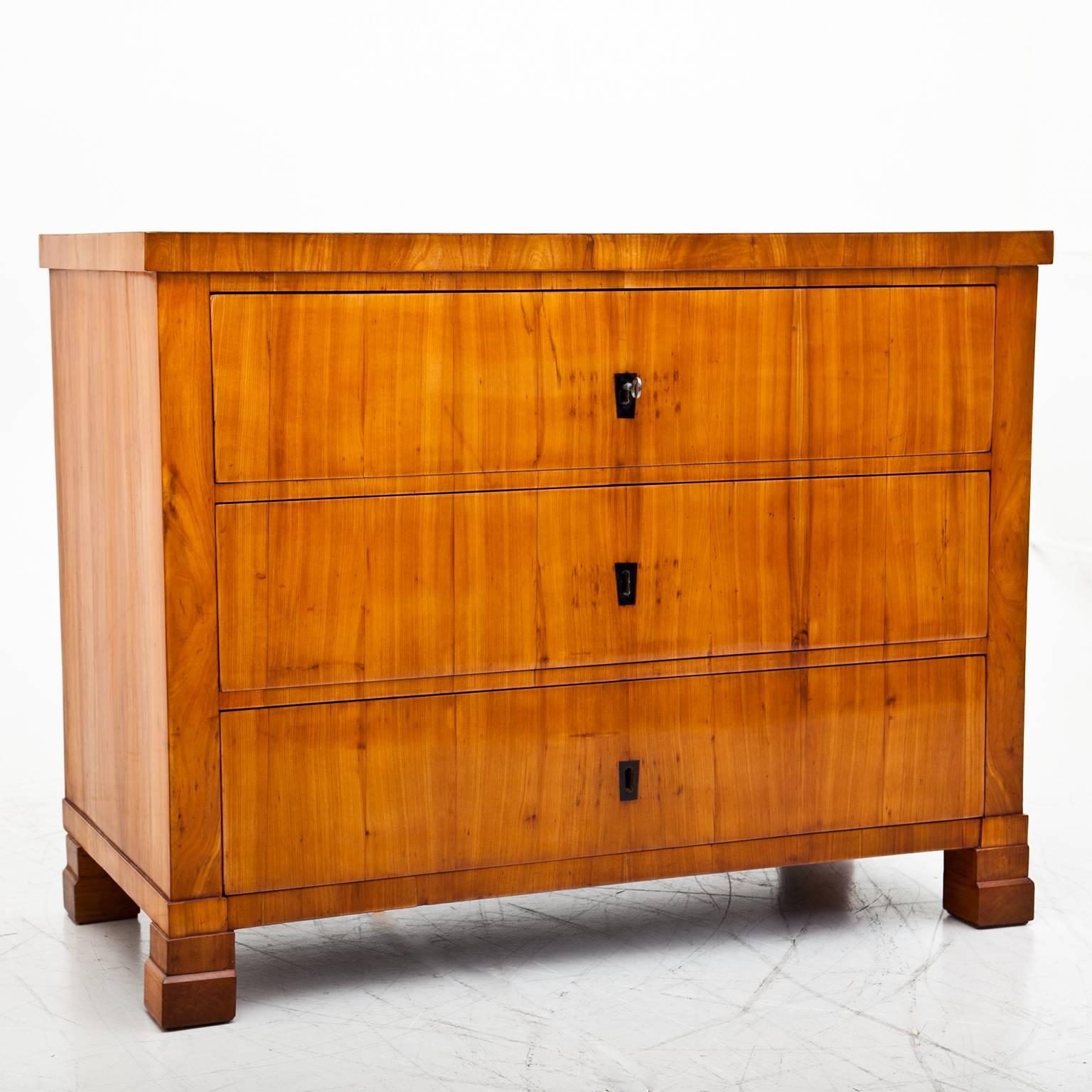 Three-drawered Biedermeier with cherrywood veneered chest of drawers with ebonized escutcheons and a streamlined body.