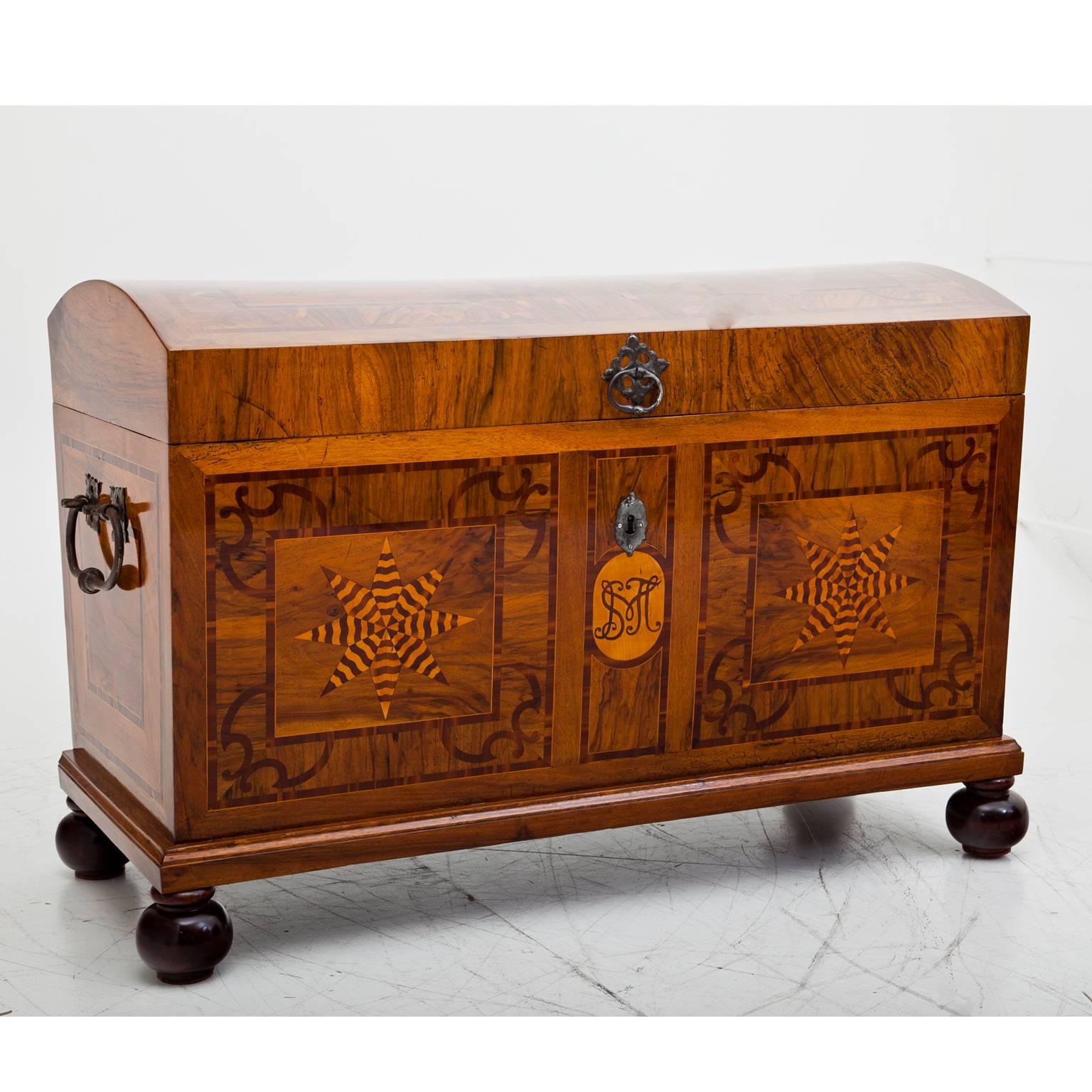 Baroque chest with iron handles and star-shaped decor at the front and on the rounded lid. The chest is beautifully inlayed and veneered with walnut as well as monogrammed SMJ at the front. The chest is in a very good restored condition. The feet