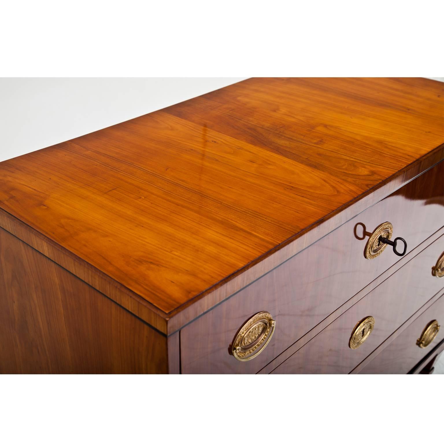 Three-drawered chest of drawers with a streamlined body and ebonized mouldings, standing on tapered feet.