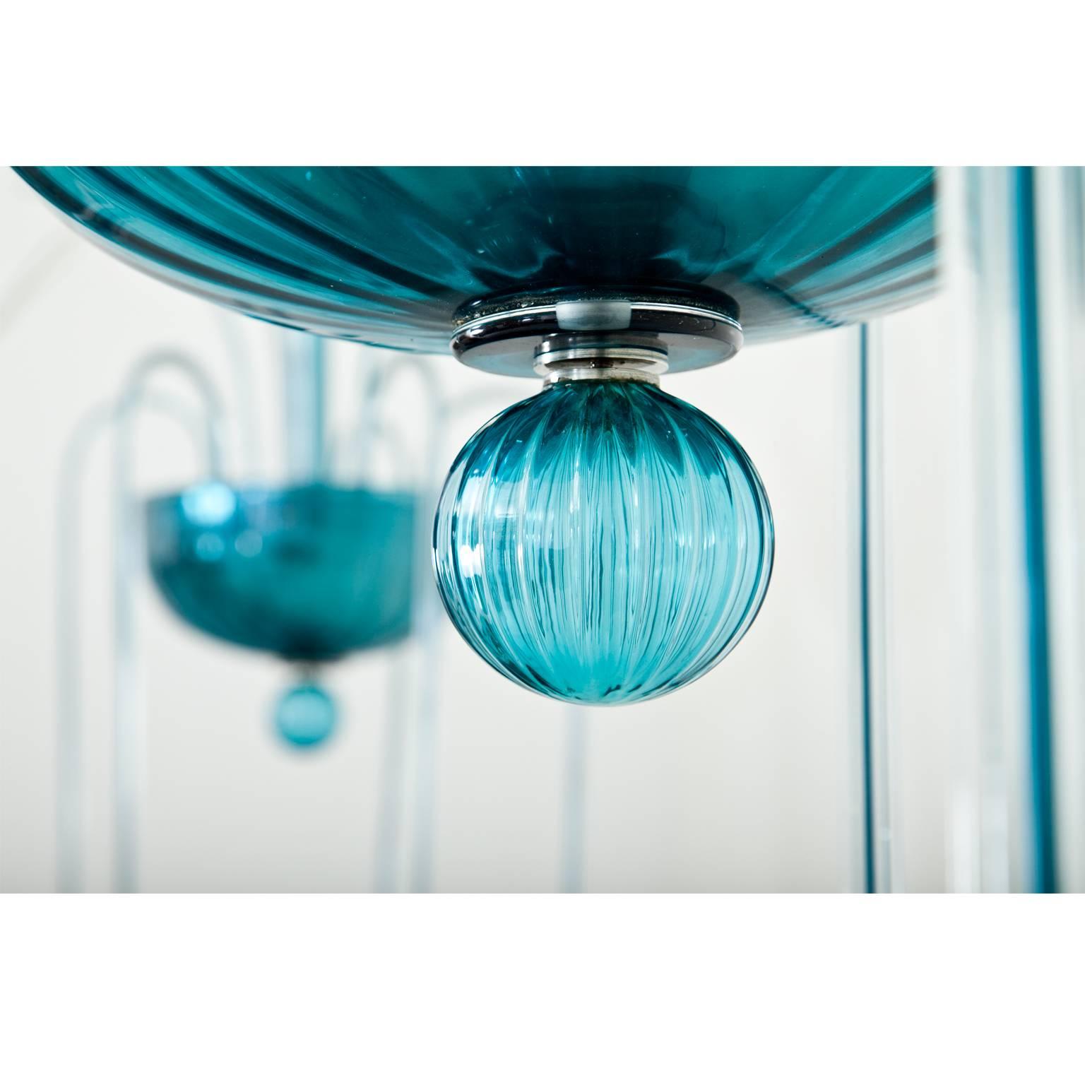 Pair of Venini "Fountain" chandeliers no. 99.35 in a very beautiful light blue. The wavy basket is decorated with a suspended glass sphere and holds ten arms out of a clear glass with blue stripes. The chandeliers are in a very good