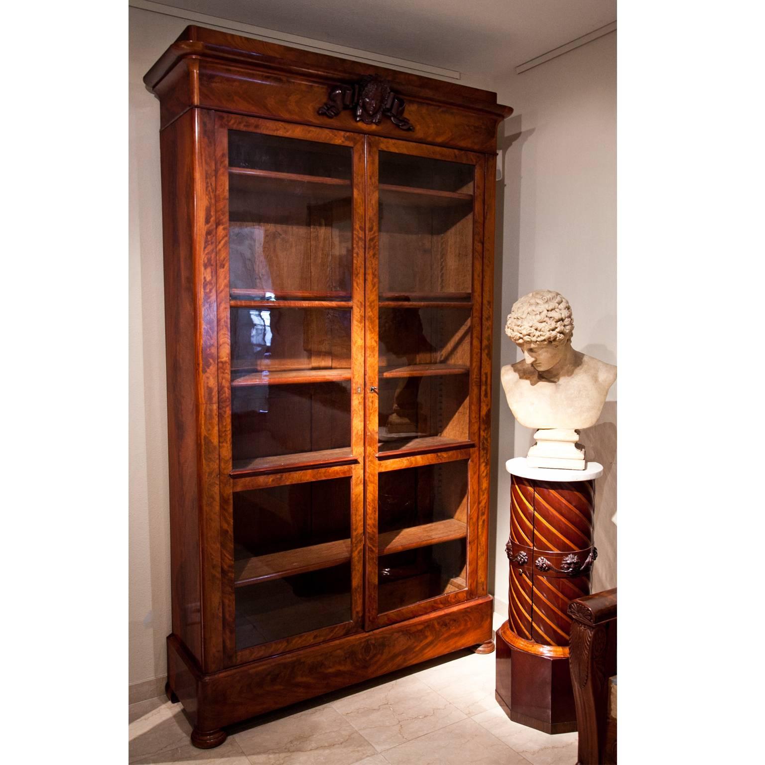 Two-doored mahogany bookcase with a straight base and a slightly protruding top, decorated with a carved female head.