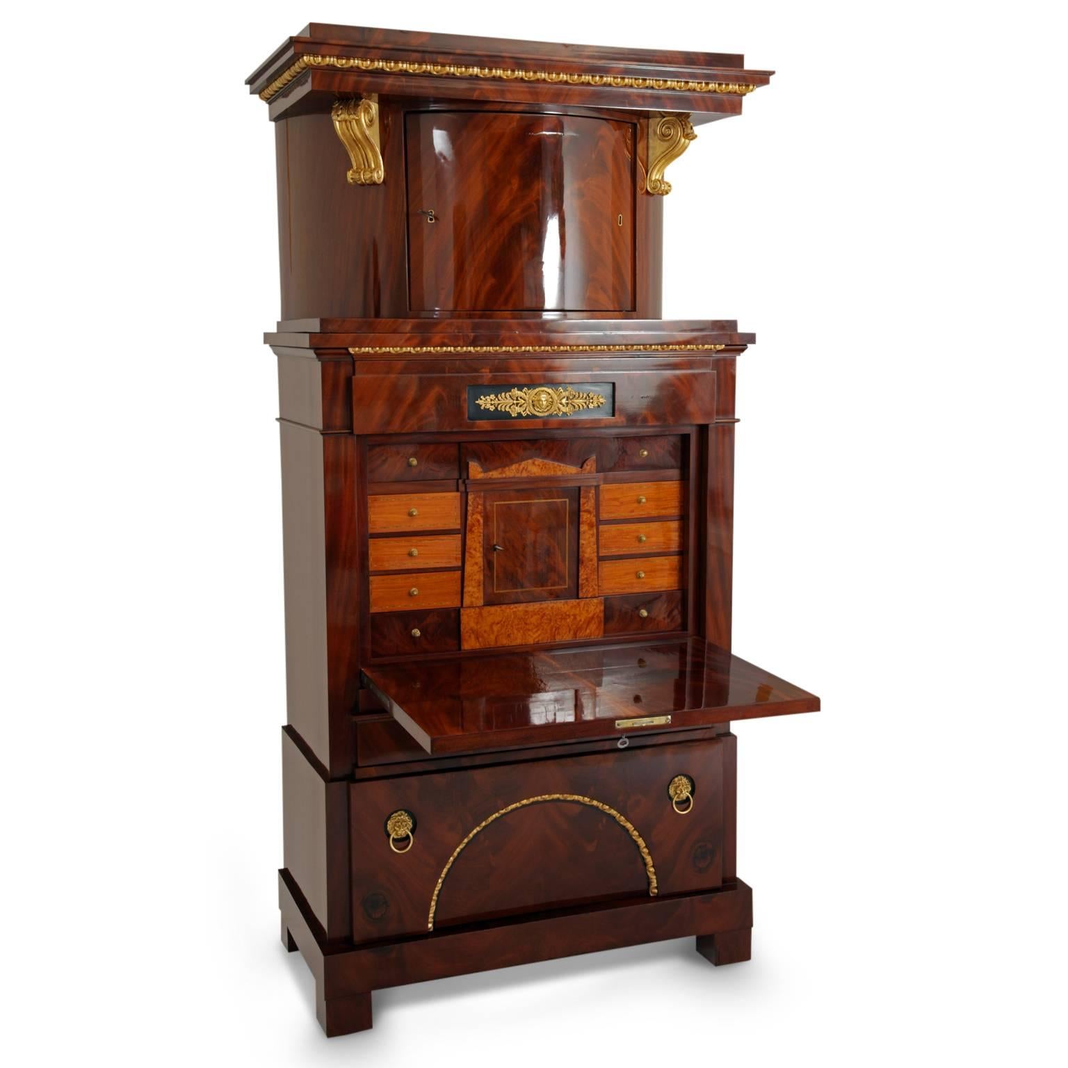 Large Empire secretary with a very beautiful flamed mahogany veneer. The body has three drawers; the interior is divided into eight drawers and one central cabinet. The rounded top is decorated with a cymatium frieze and volutes and the middle