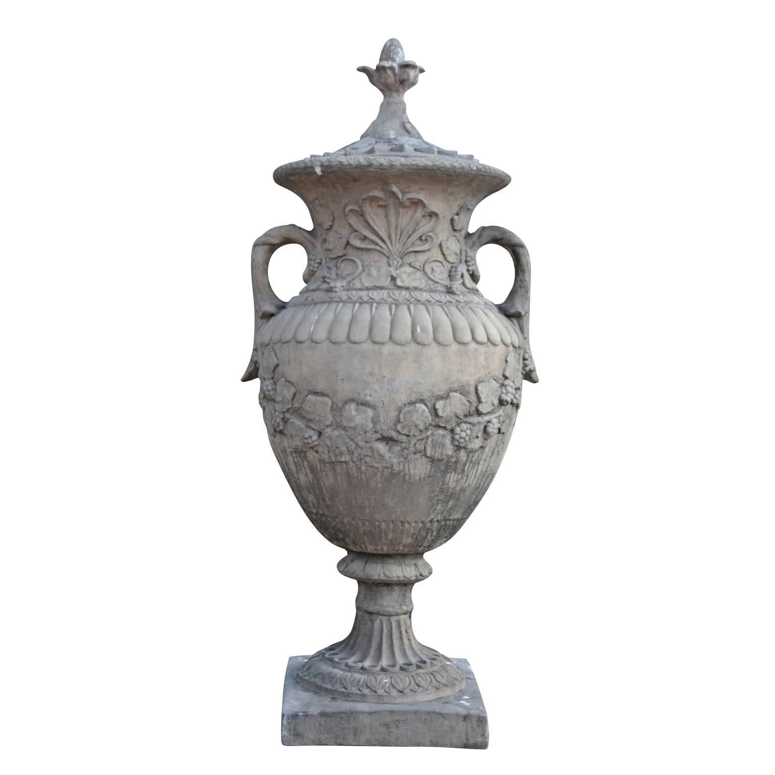 The urn stands on a square plinth and has a round foot with cymatium and tongue-elements. The wall of the body is decorated with vines and the handles are shaped like leaves. The neck is decorated with an acanthus leaf and additional vines. The top