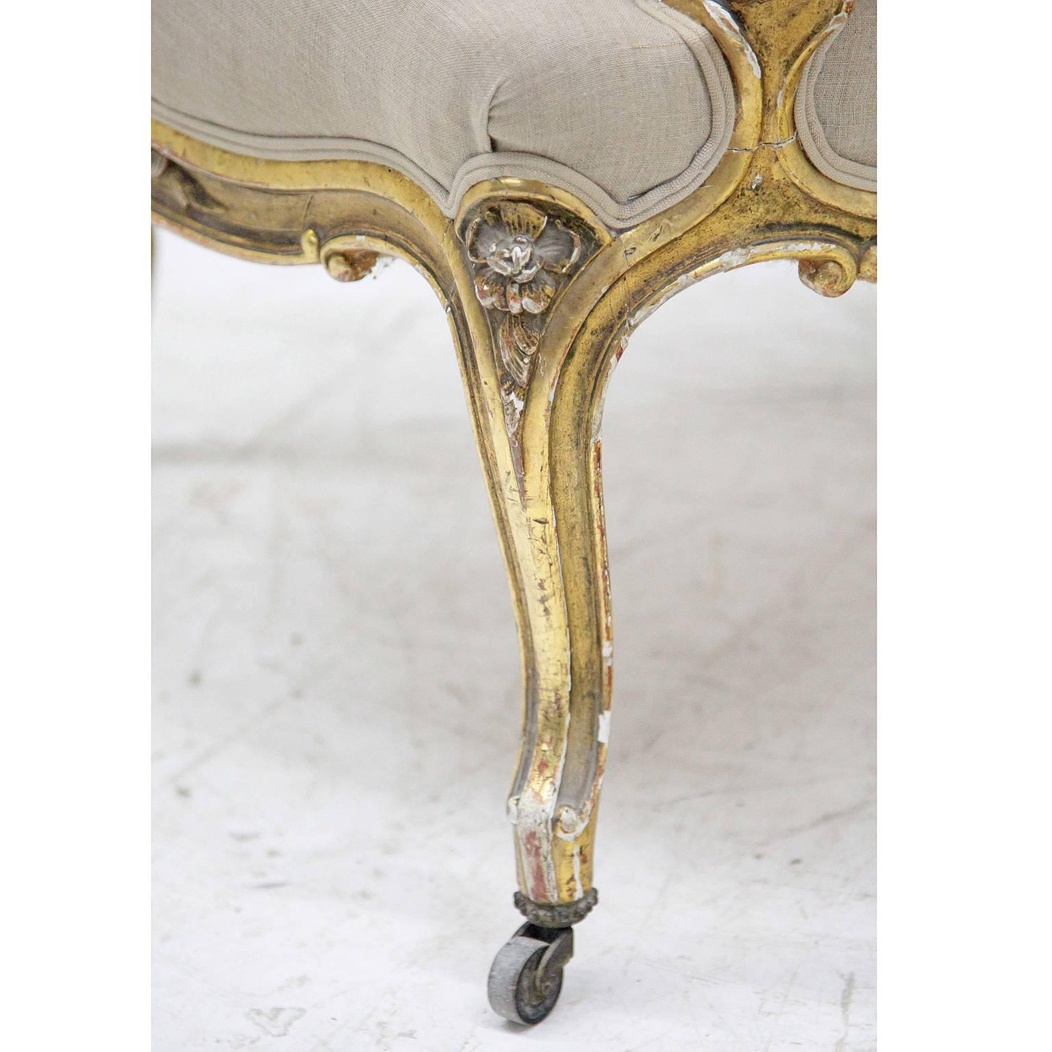 Un fauteuil Napoléon III sur des pieds en forme de S avec un cadre incurvé. Le dossier haut et arrondi ainsi que l'assise et les accoudoirs sont rembourrés. Le cadre patiné doré est décoré d'éléments floraux sculptés.