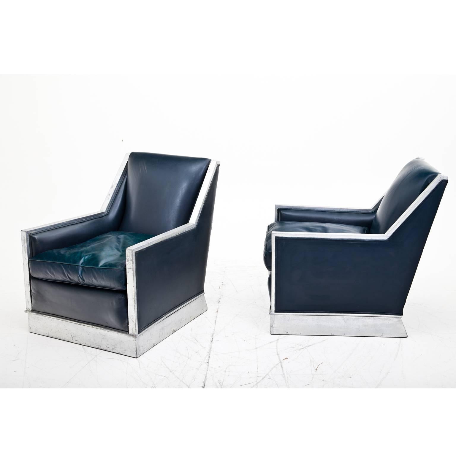 Pair of Art Deco armchairs in an original condition with silvered armrests and stands. The armchairs are upholstered with an old dark blue leather and the silver was carefully cleaned.