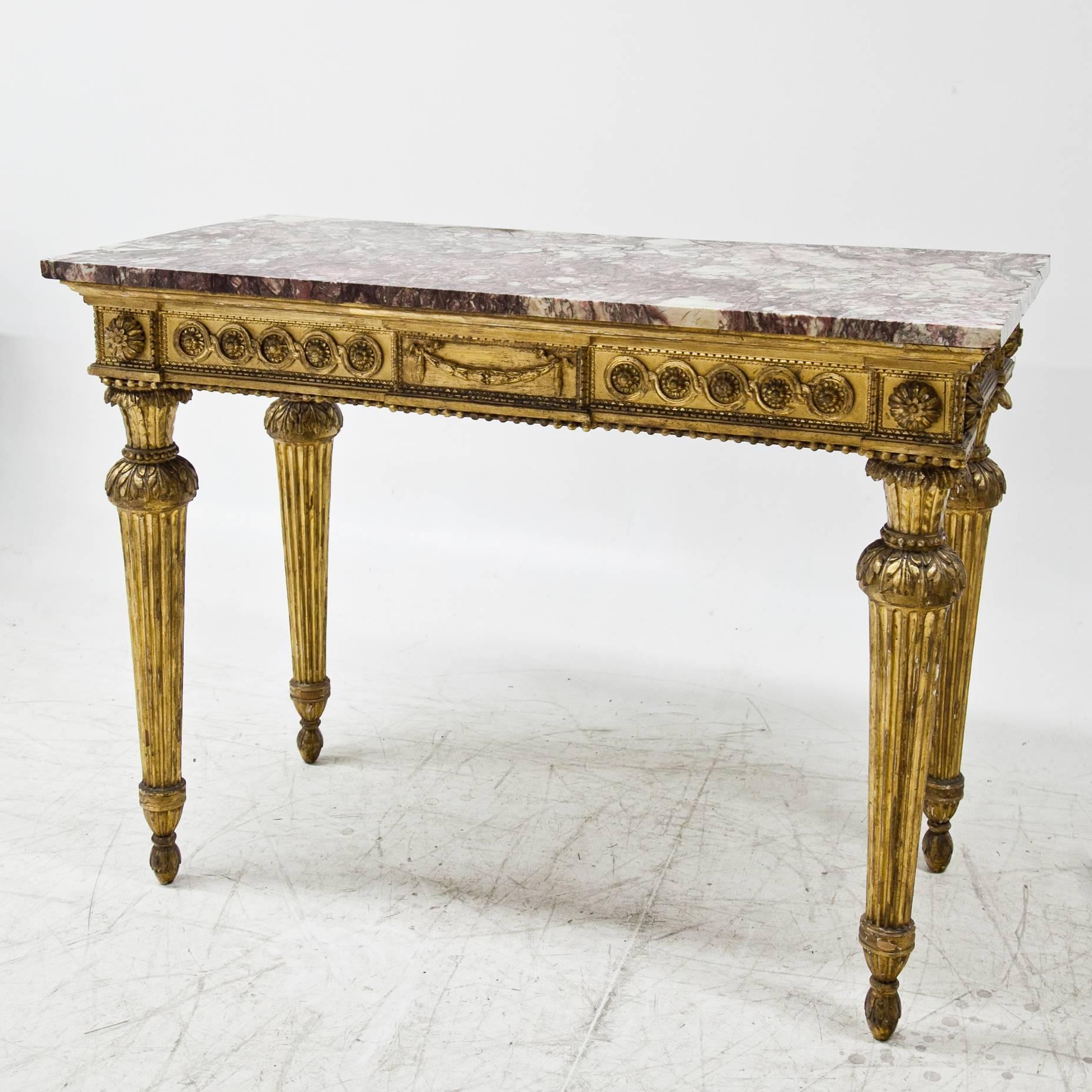 Gilt Louis Seize console table on fluted legs, the front rail is decorated with interlaced ornaments, flowers, festoons and beads. The red and white marble top completes this beautiful piece of furniture, it was added later in the 19th century.
