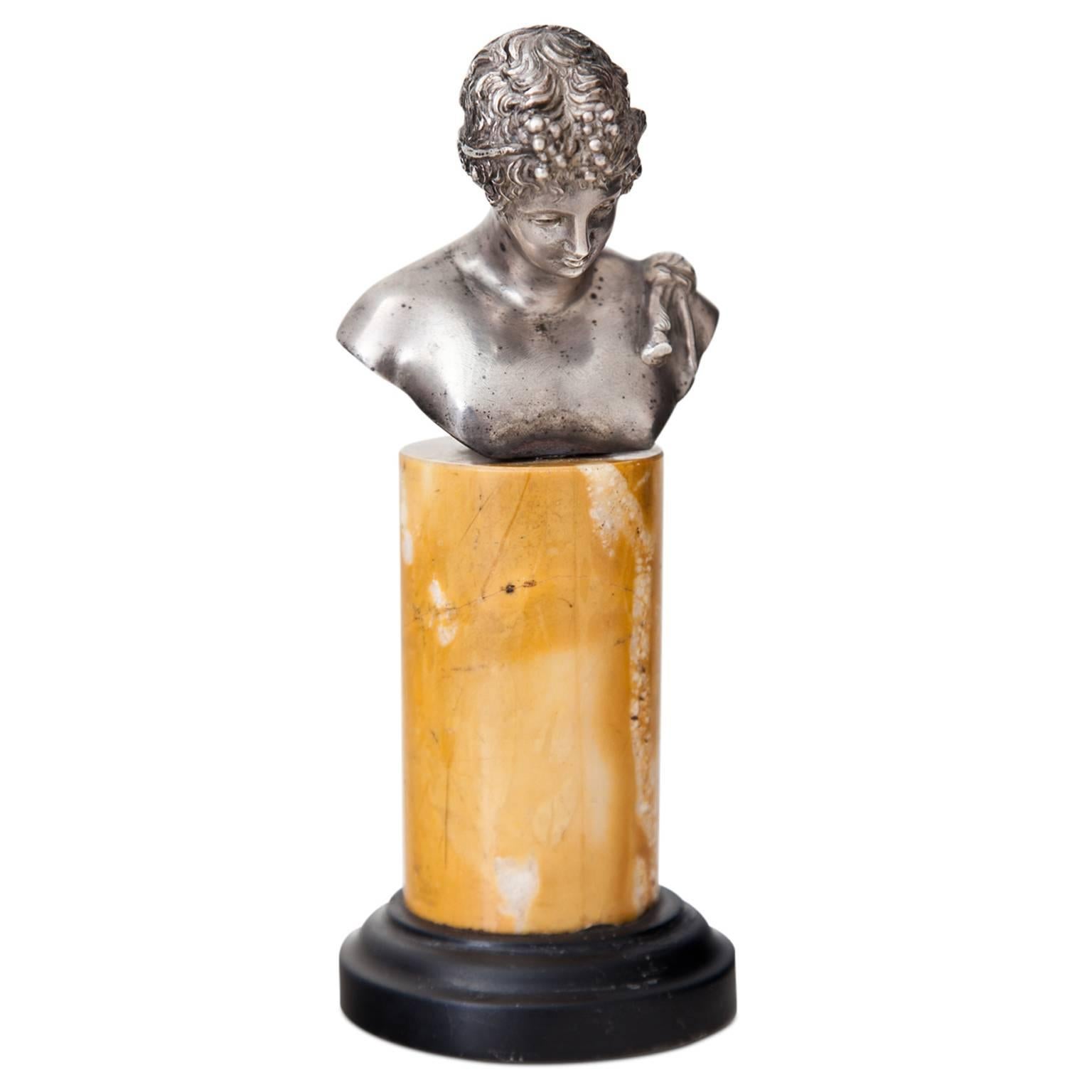 Small bust of Dionysus, so-called Narcissus of Pompeii on cylindrical yellow marble pedestal with a black base.