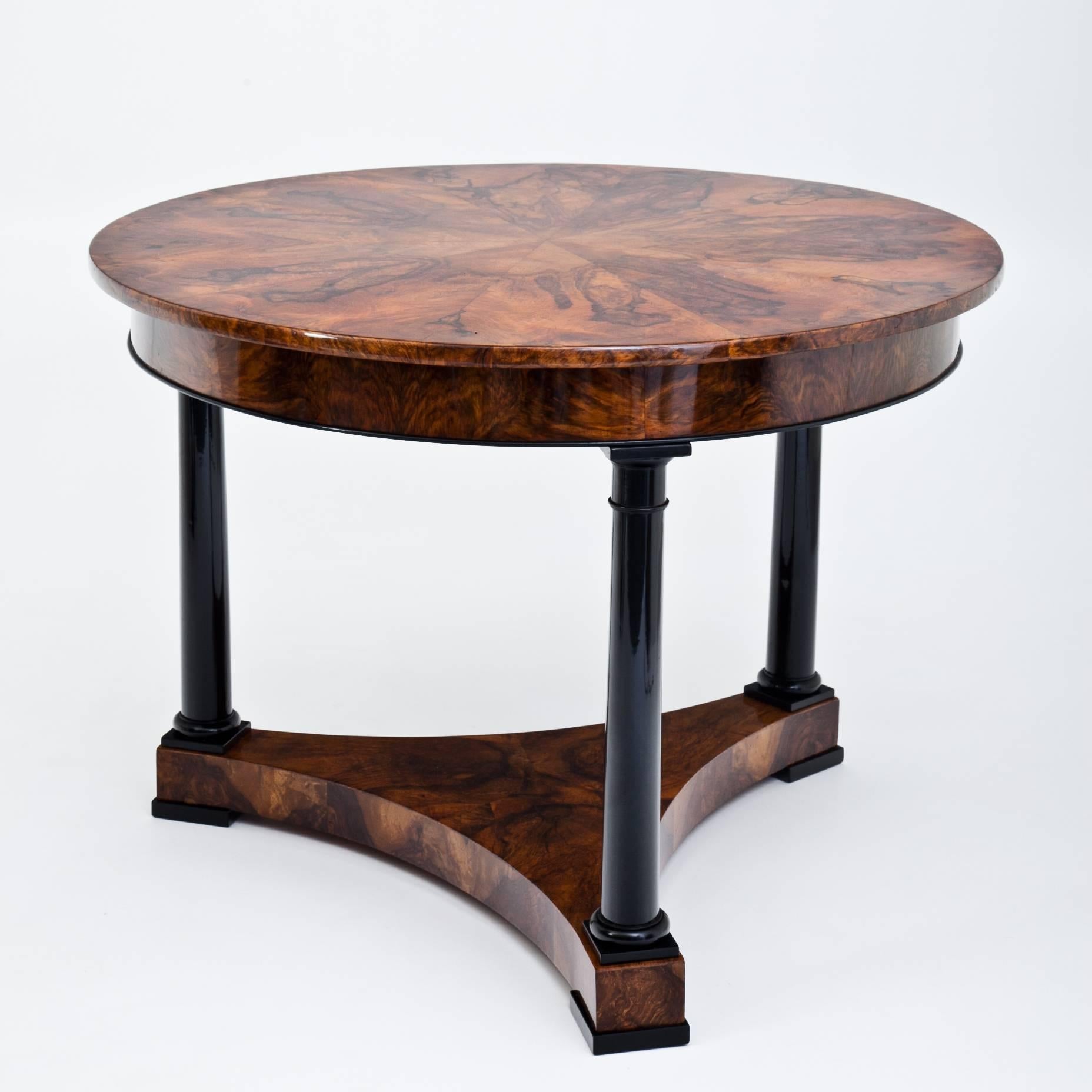 Biedermeier salon table in a museum-like quality on a trefoil base. The legs are in the shape of ebonized Tuscan columns. Extraordinary walnut veneer pattern at the tabletop.