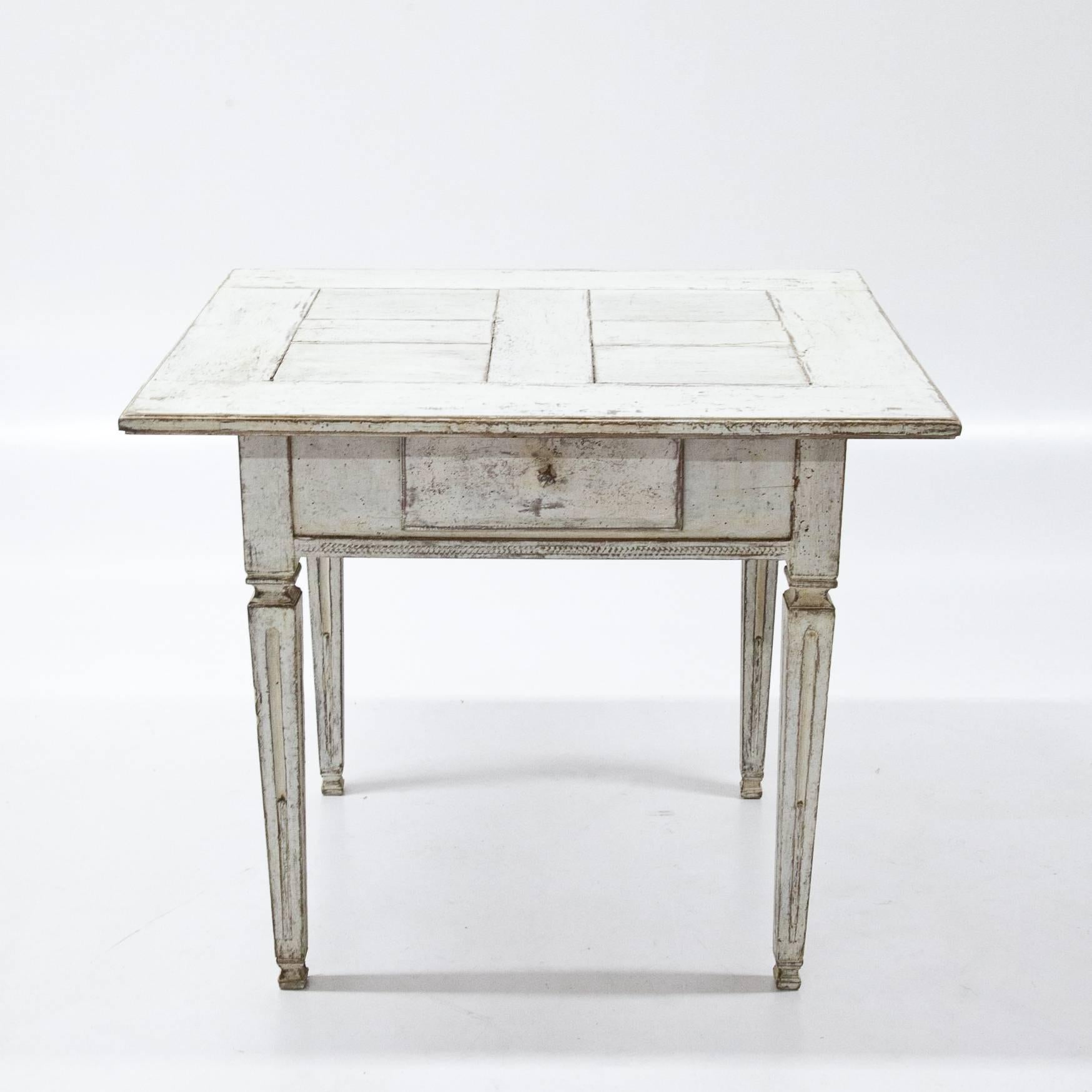 Provençal table on fluted tapered legs, with one drawer and a parqueted tabletop. The white paint has a slightly worn look giving the piece lots of character.