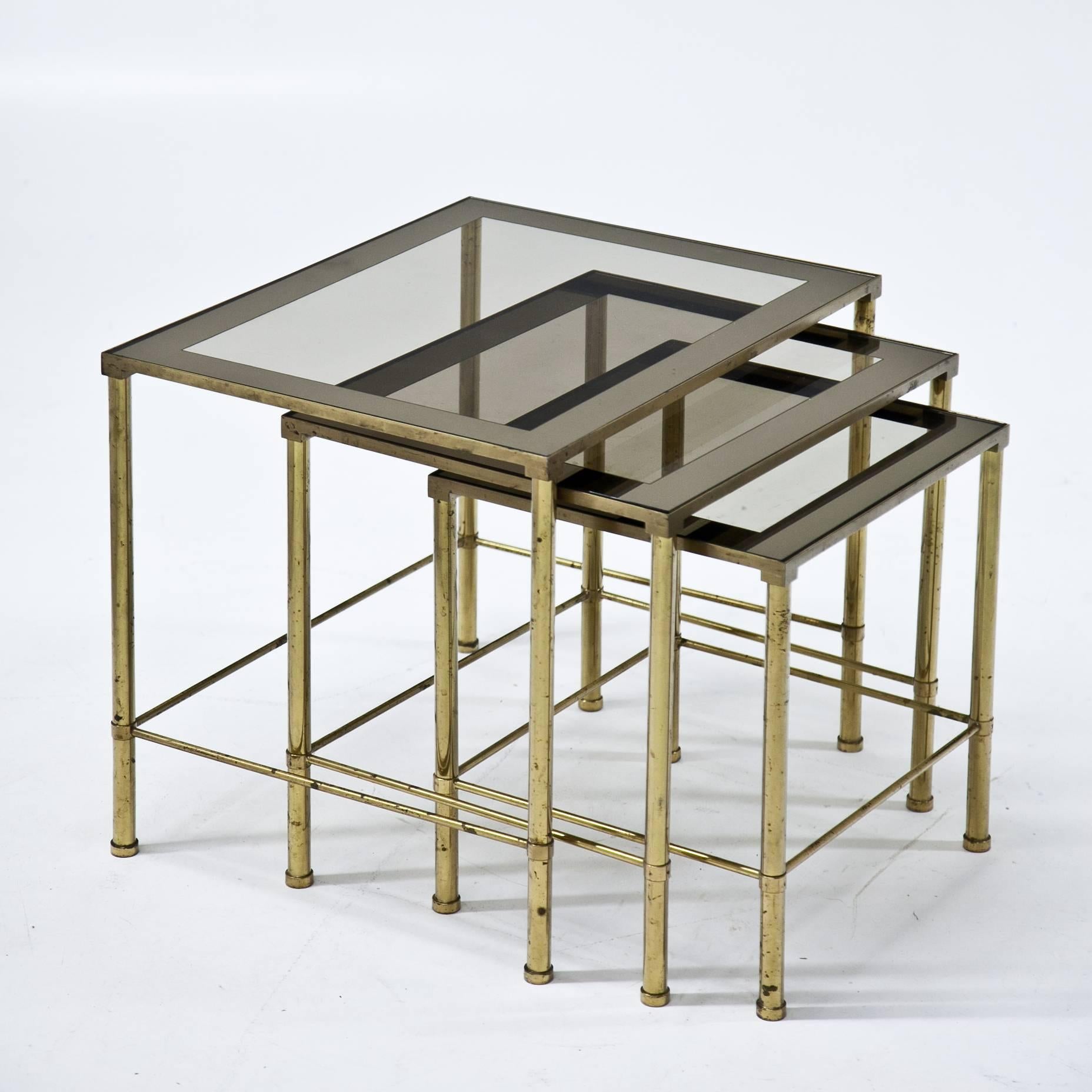 Italian Nesting tables with slightly tinted glass tops, standing on round brass feet.