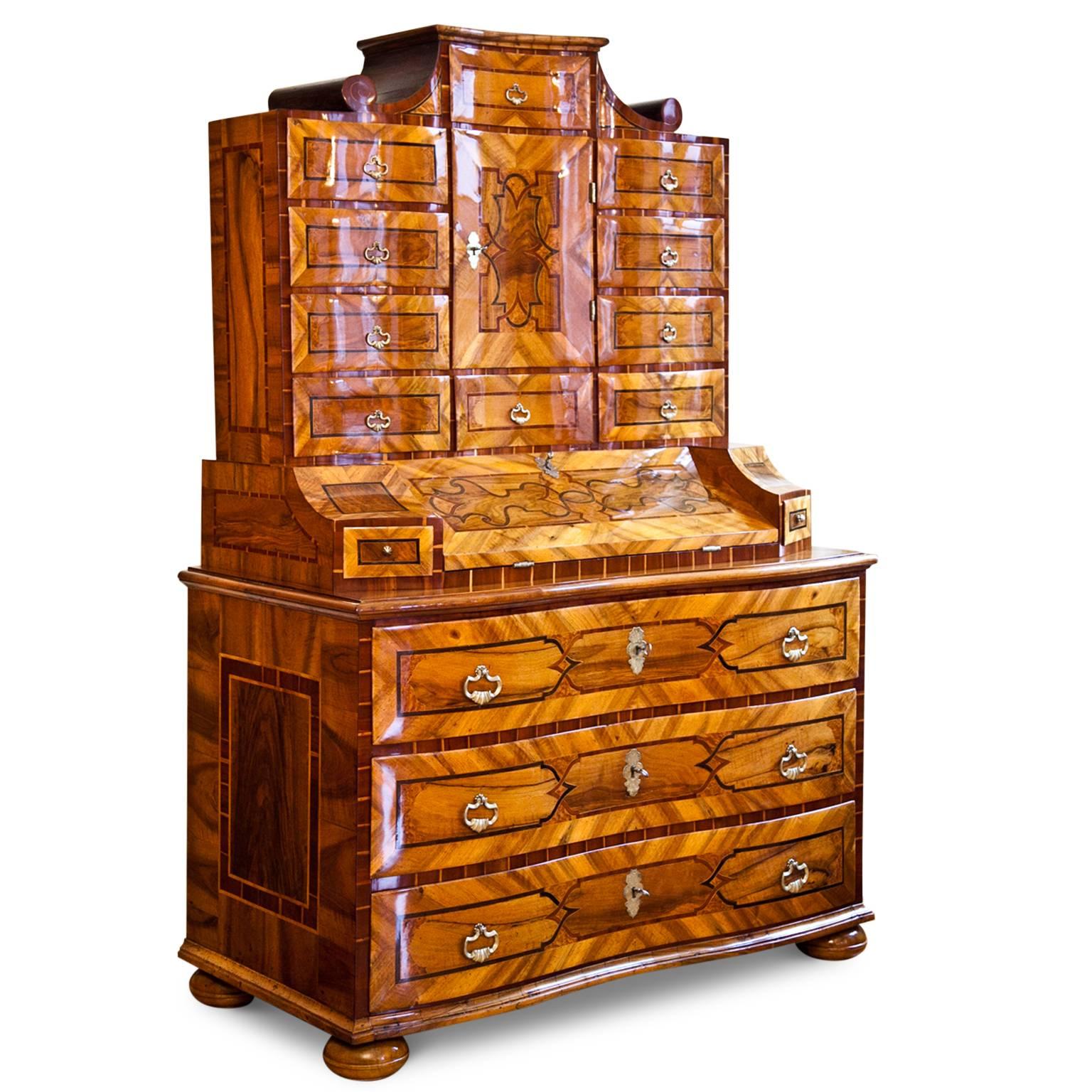 Baroque Tabernacle Secretaire on bun feet with a three-drawered chest of drawers base and a serpentine front. The writing surface is at a height of 87.5 cm and has three more drawers on the inside. The top part shows multiple drawers and a raised