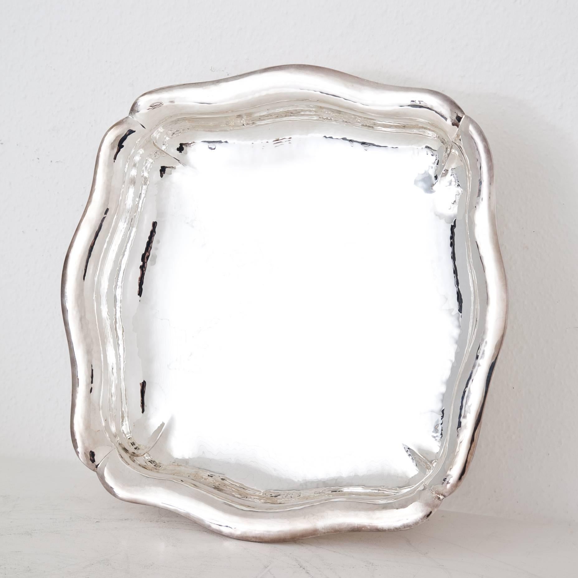 Large square silver dish on low feet, with a serpentine wall and smooth well. Marked at the bottom with halfmoon and crown, 
