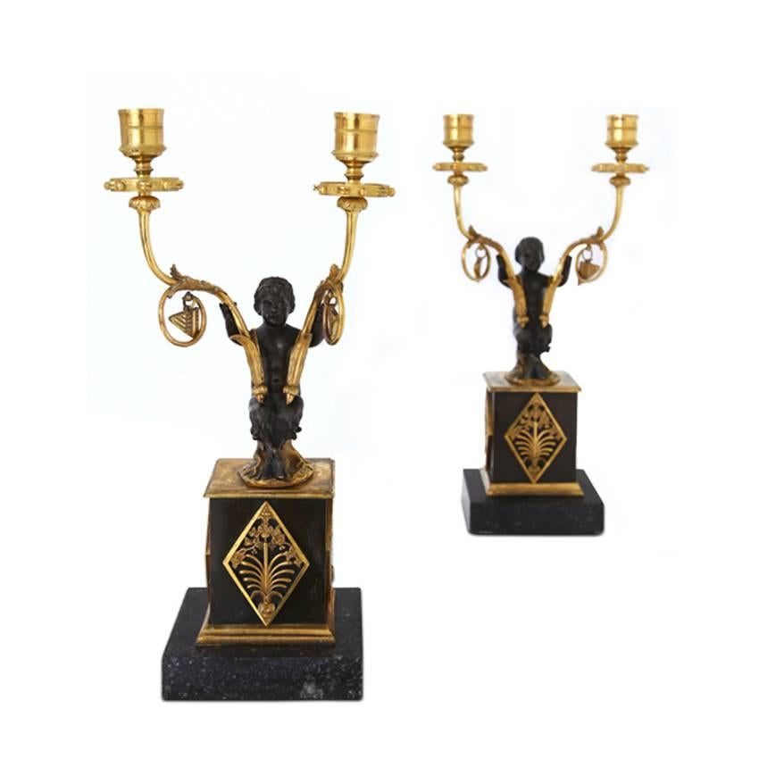 Pair of French Empire candlesticks on a square black marble plinth. Little bronze satyrs carry the gilt candle arms.