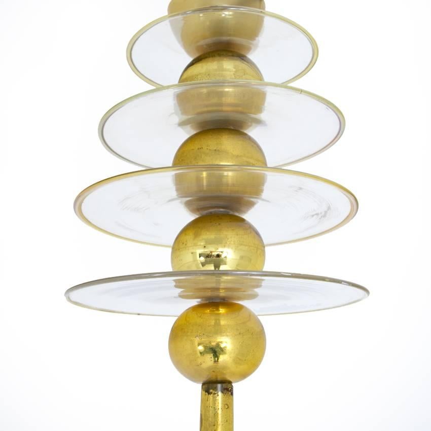 Italian pendant light with a blown conical glass shade on a long brass rod. The lamp is decorated at the top with brass balls that are separated by thin glass disks with gold rim. The brass shows some signs of age.

For the electrification we assume