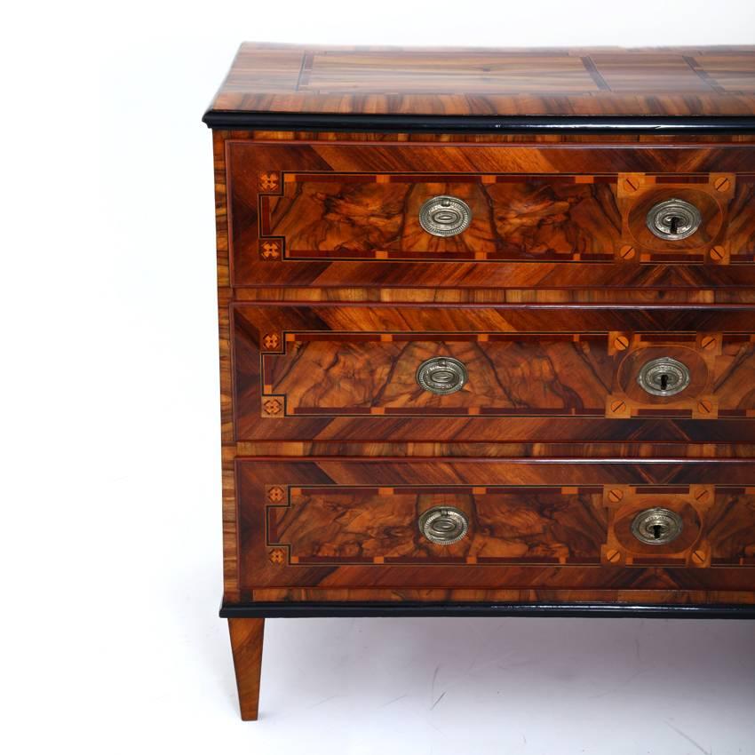Three-drawered walnut Louis seize chest of drawers on tapered feet. The straight body has ebonised edges and very beautiful inlays all around.