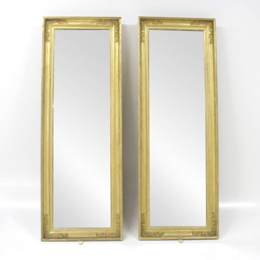 Pair of large wall mirrors in gilt frames with stucco ornaments in the corners. Size of mirror pane: 177 x 50 cm.