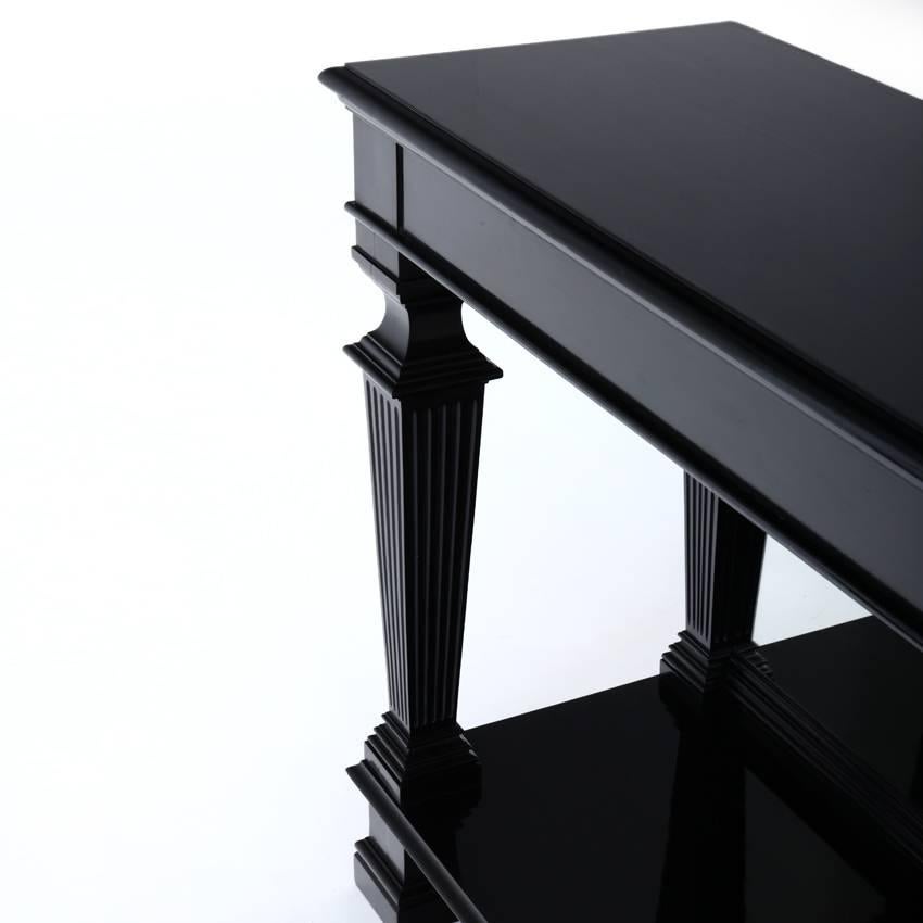 Ebonized neoclassical console table of the second half of the 19th century. The black console has two fluted pillars in the front and pilasters in the back. The rear wall is mirrored.