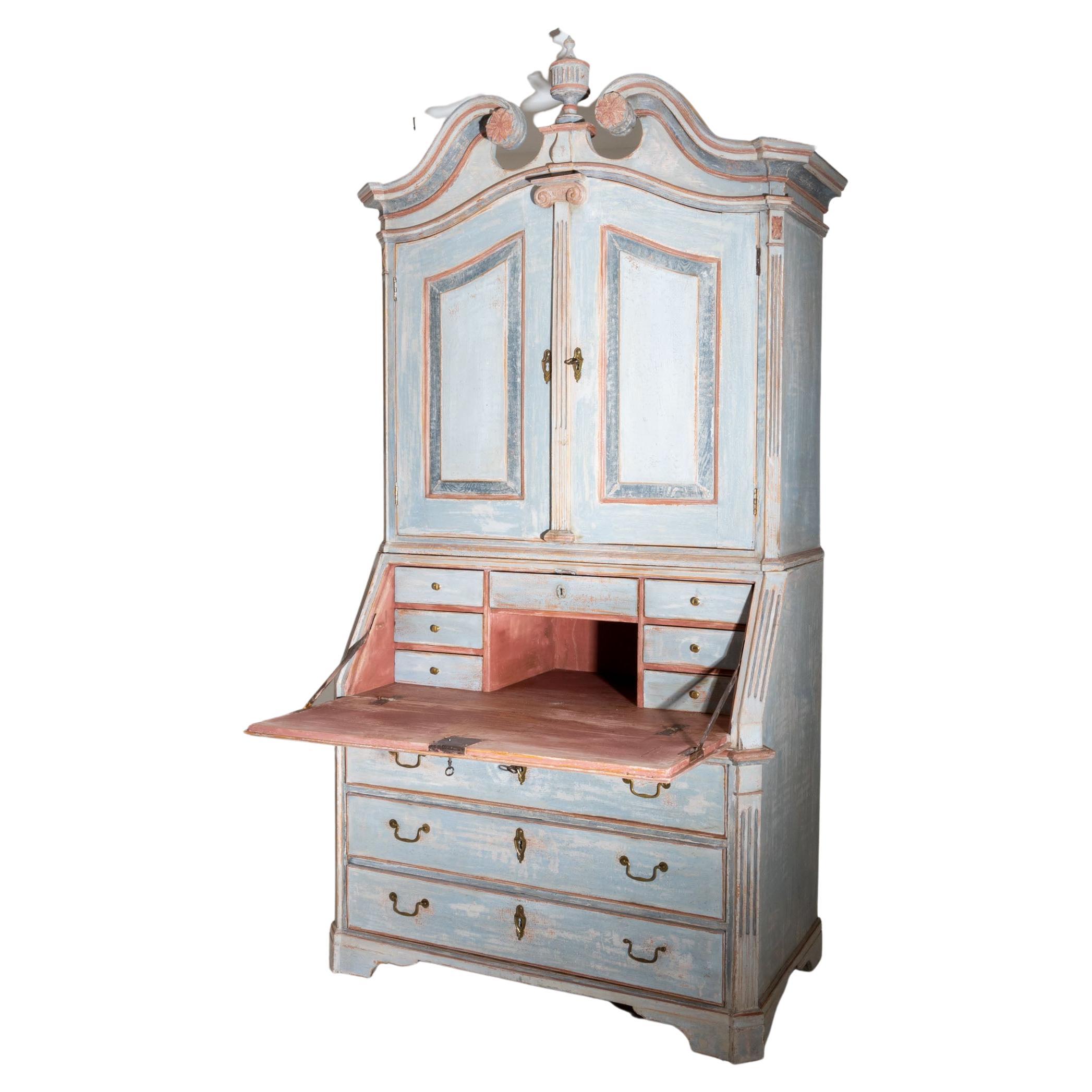 Hand painted top secretary with slanted flap and three-panel commode base as well as two-door top with swan-neck pediment and central urn motif. The interior consists of smaller drawers. The light blue frame with brick red accents is new and has