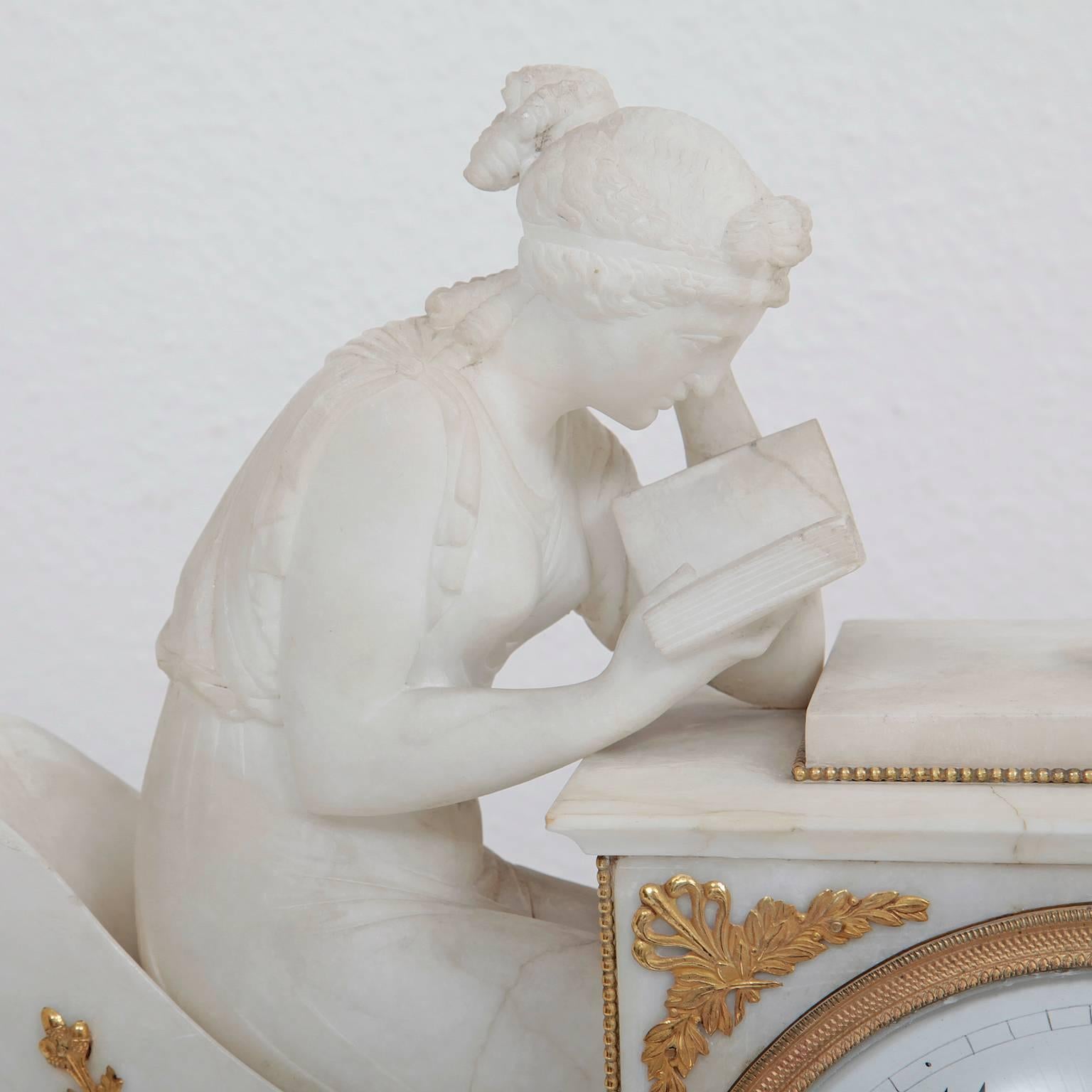 Marble Case with fire gilded classicist bronze-ornaments as well as an enamel clock face with Arabic numerals. A marble figure of a young, reading woman on an armchair completes this clock on its left side.