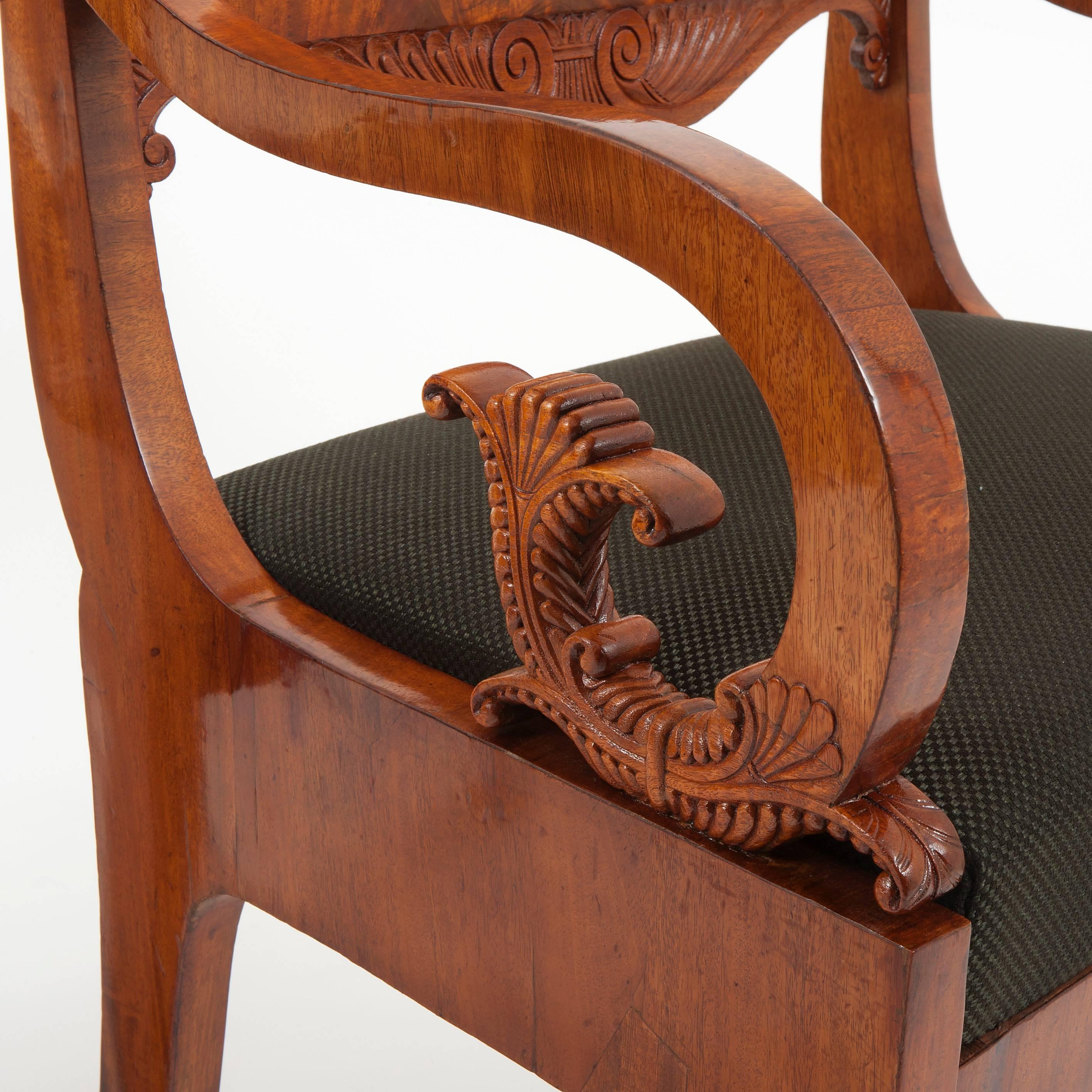 A pair of armchairs on flared legs with short backrests. The backrests are decorated with balusters and rocaille details. The armrests have been masterfully carved.