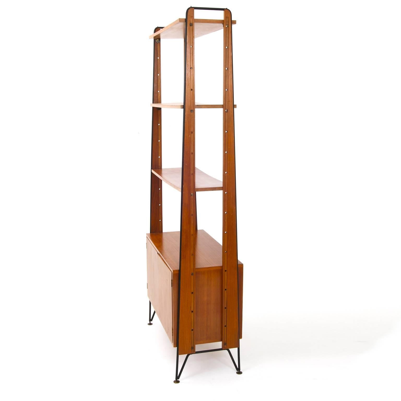 An open shelf system on metal strutting with round brass feet. The piece has three adjustable shelves and a cabinet with two doors. On the inside is a stamp from the company Mobilifico Cicchetti from Genua.