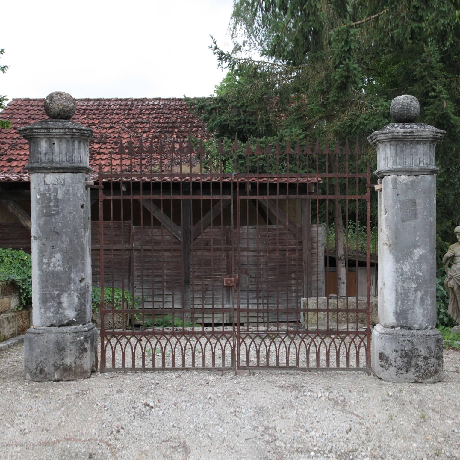 Large iron gate with two stone pillars. The gate topped with arrow shaped pieces. This gate has a lovely old patina.