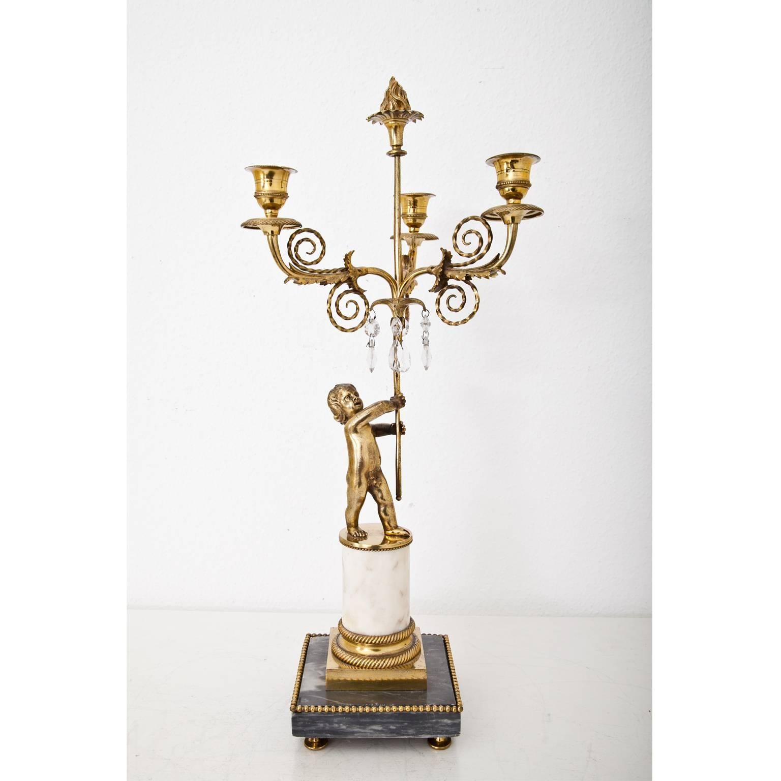Three-armed candelabra with putto out of gilt bronze on a grey and white marble base.