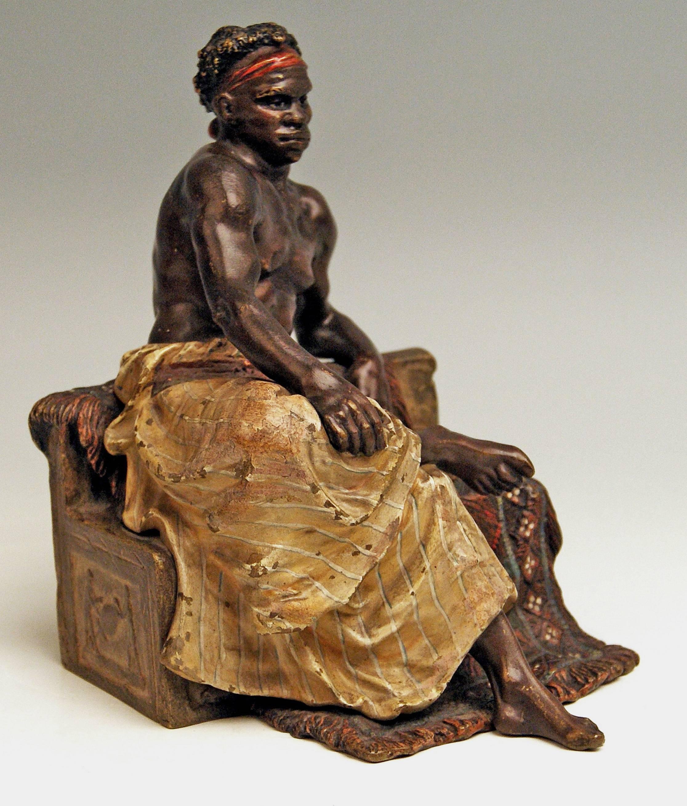 Stunning bronze figurine: Black man having sat down on bench.
 
This excellent Vienna bronze figurine is of finest manufacturing quality: 
It is a black handsome young man with red ribbon in curled hair / his upper body is unclad, the lower body