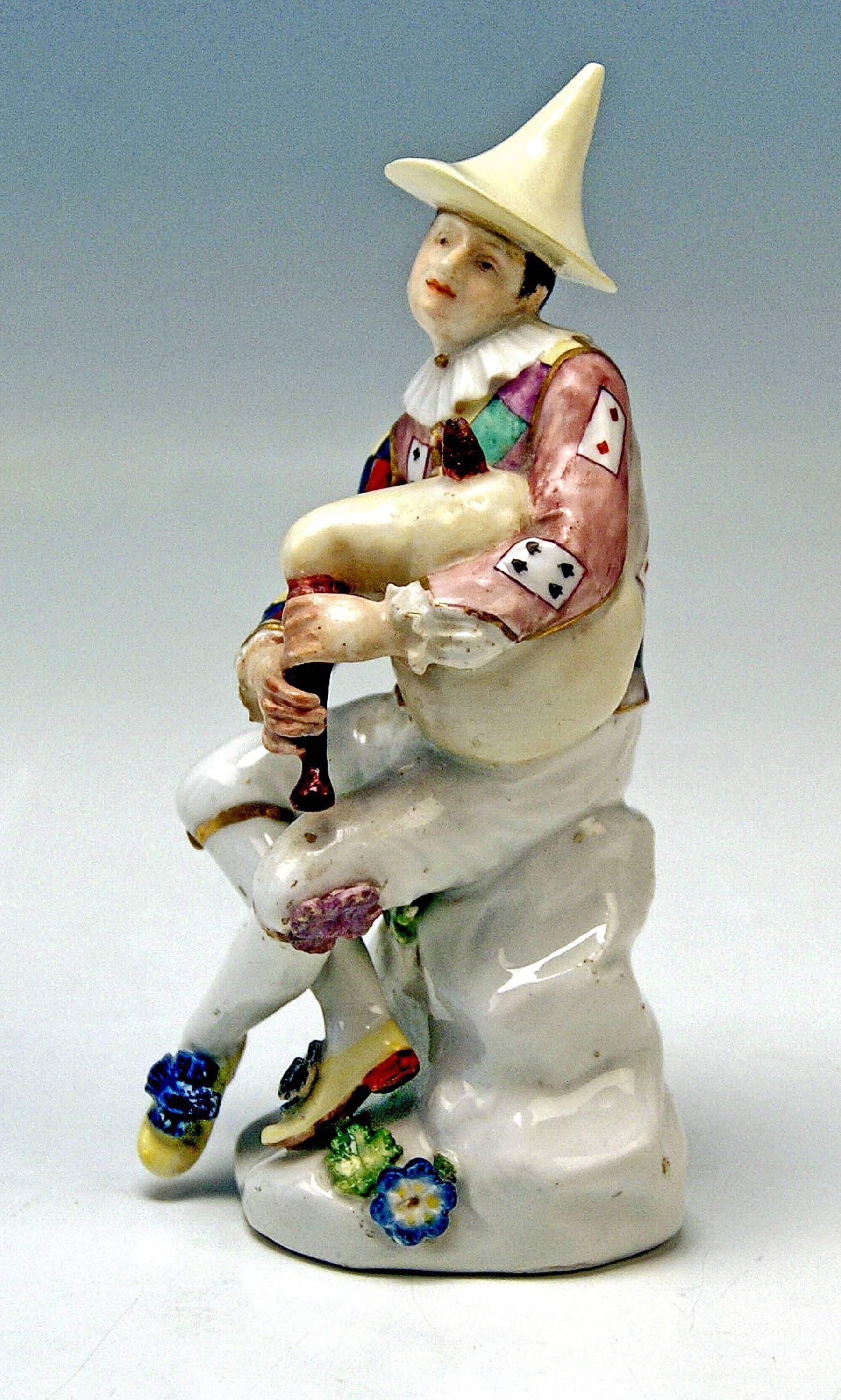 Meissen Rococo harlequin with bagpipes of most lovely appearance.:
The lovely harlequin is sitting on a rocky base which is decorated with some flower blossoms with leaves. The male figurine seizes bagpipes with both hands, seeming to be a bit