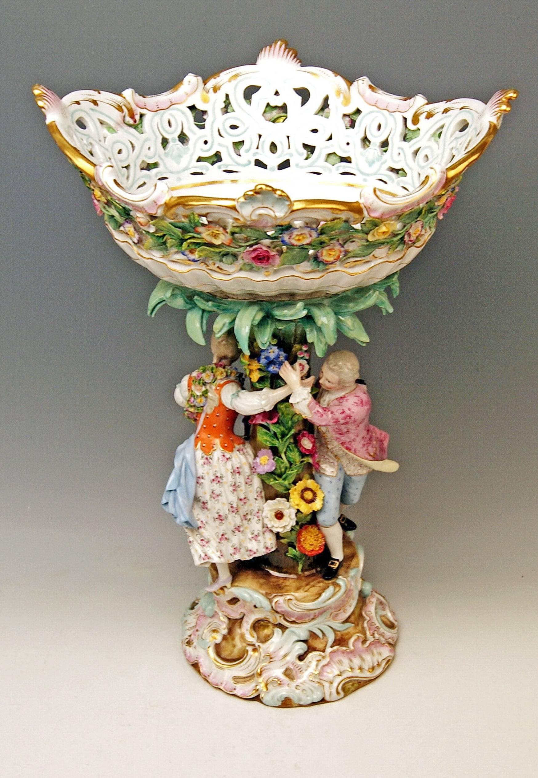 Meissen stunning as well as quite rare item:
Meissen gorgeous tall centrepiece, surrounded by Two dancing gardener figurines, with reticulated (scalloped) bowl

Measures / dimensions:
total height: 49.5 cm (= 19.48 inches) 
total width: 33.0 cm