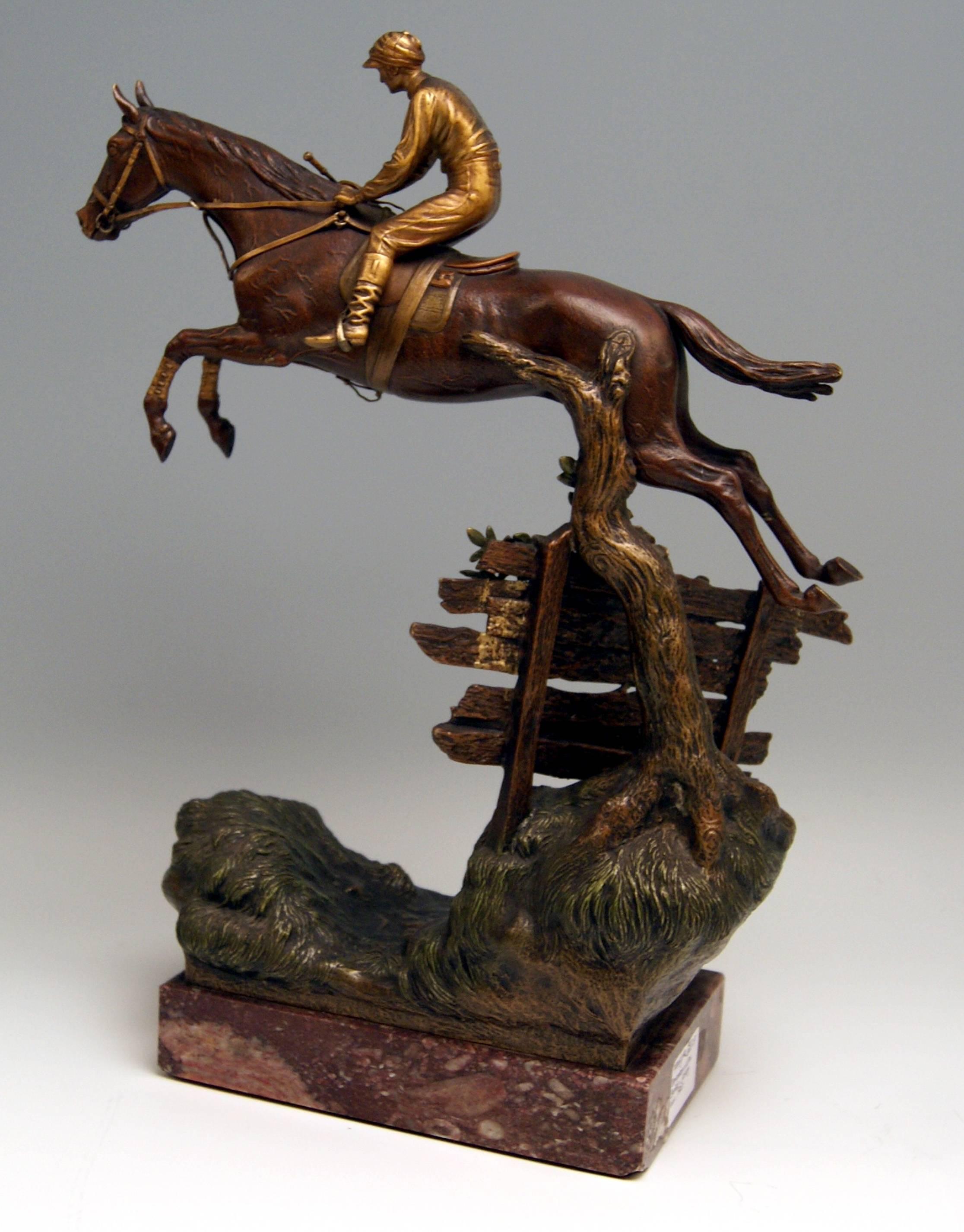 Wunderschöne große Wiener Bronzefigur der berühmten Manufaktur Bergman(n) um 1920. 
Der Jockey in typischer Kleidung (= Mütze, Reitstiefel, Reithose und Hemd) führt das Pferd an den Zügeln: Das Pferd springt über einen Zaun, der auf grasbewachsenem