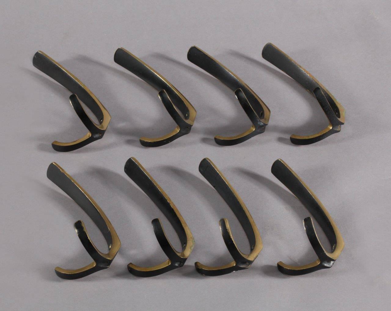 Eight simple and elegant wall-mounted brass hooks, with a contrasting faux patina. Having a large upper hook and two small lower hooks.

Designed by Carl Auböck.
Manufactured by Carl Auböck,
Vienna, 1950.