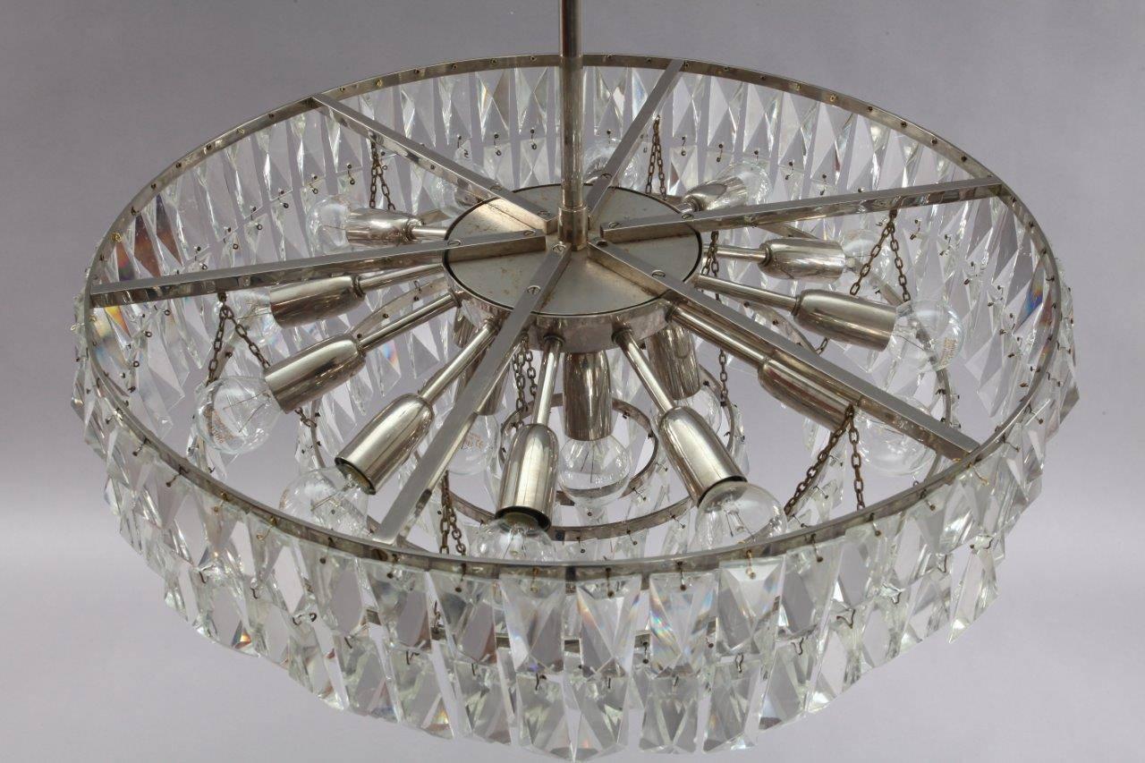 Impressive and stunning crystal chandelier from about 1960s by Bakalowits & Söhne. Brass construction nickel-plated with five rings with hand-cut crystals in rombform. Electric with 12 light sources with two circuits. 
Dimensions: diameter 60cm